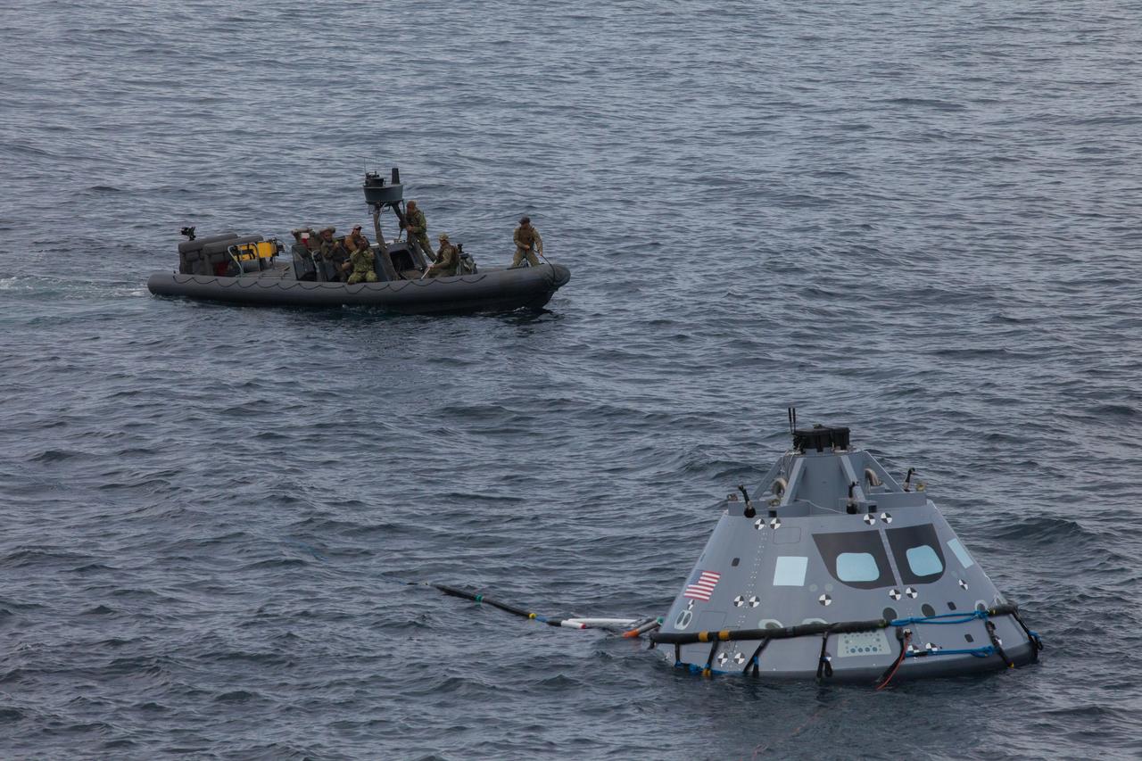 A test version of the Orion crew module floats in the Pacific Ocean during Underway Recovery Test 5 in the Pacific Ocean off the coast of California on Oct. 30, 2016. Nearby are U.S. Navy divers and other personnel in a rigid hull inflatable boat. NASA's Ground Systems Development and Operations Program and the U.S. Navy are conducting a series of tests using the well deck of the USS San Diego, several watercraft, support equipment and personnel to prepare for recovery of Orion on its return from deep space missions. The testing will allow the team to demonstrate and evaluate recovery processes, procedures, hardware and personnel in open waters. Part of Batch images transfer from Flickr. 
