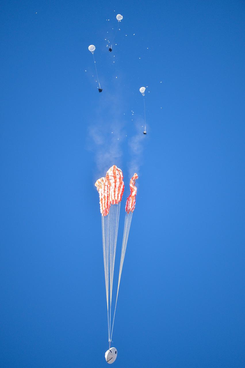 Orion’s three main orange and white parachutes help a representative model of the spacecraft descend through sky above Arizona, where NASA engineers tested the parachute system on Sept. 13, 2017 at the U.S. Army Proving Ground in Yuma. NASA is qualifying Orion’s parachutes for missions with astronauts.. .During this test, engineers replicated a situation in which Orion must abort off the Space Launch System rocket and bypasses part of its normal parachute deployment sequence that typically helps the spacecraft slow down during its descent to Earth after deep space missions. The capsule was dropped out of a C-17 aircraft at more than 4.7 miles in altitude and allowed to free fall for 20 seconds, longer than ever before, to produce high aerodynamic pressure before only its pilot and main parachutes were deployed, testing whether they could perform as expected under extreme loads. Orion’s full parachute system includes 11 total parachutes -- three forward bay cover parachutes and two drogue parachutes, along with three pilot parachutes that help pull out the spacecraft’s three mains.