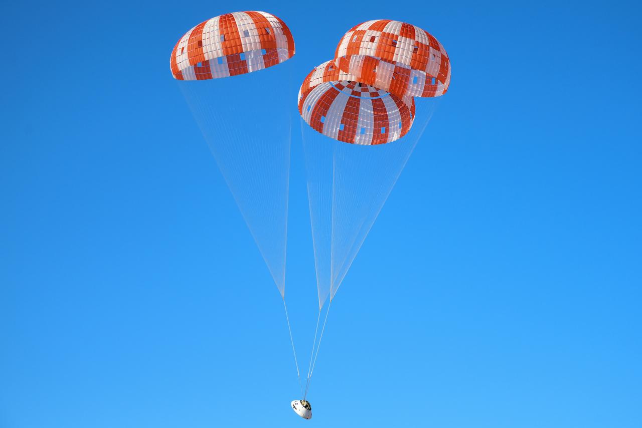 Orion’s three main orange and white parachutes help a representative model of the spacecraft descend through sky above Arizona, where NASA engineers tested the parachute system on Sept. 13, 2017 at the U.S. Army Proving Ground in Yuma. NASA is qualifying Orion’s parachutes for missions with astronauts.. .During this test, engineers replicated a situation in which Orion must abort off the Space Launch System rocket and bypasses part of its normal parachute deployment sequence that typically helps the spacecraft slow down during its descent to Earth after deep space missions. The capsule was dropped out of a C-17 aircraft at more than 4.7 miles in altitude and allowed to free fall for 20 seconds, longer than ever before, to produce high aerodynamic pressure before only its pilot and main parachutes were deployed, testing whether they could perform as expected under extreme loads. Orion’s full parachute system includes 11 total parachutes -- three forward bay cover parachutes and two drogue parachutes, along with three pilot parachutes that help pull out the spacecraft’s three mains.