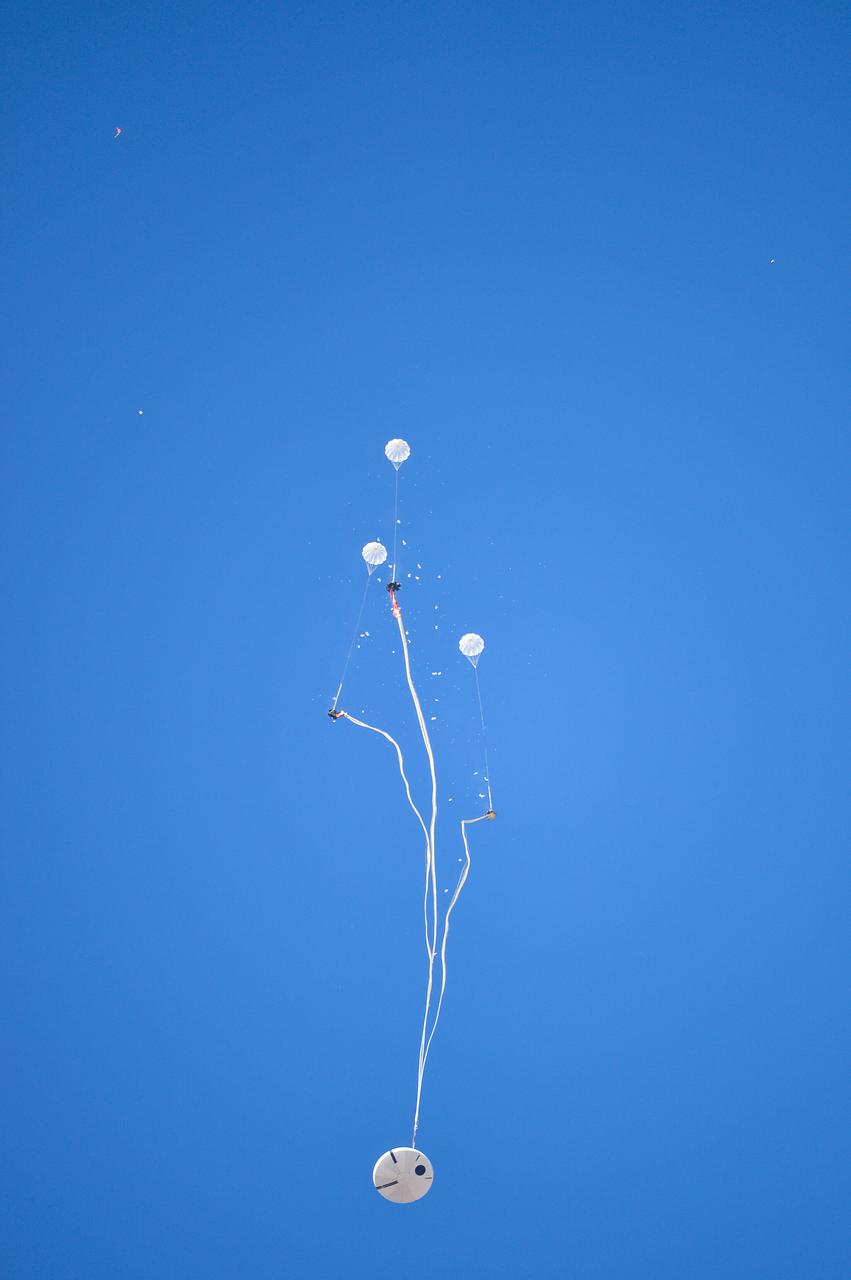 Orion’s three main orange and white parachutes help a representative model of the spacecraft descend through sky above Arizona, where NASA engineers tested the parachute system on Sept. 13, 2017 at the U.S. Army Proving Ground in Yuma. NASA is qualifying Orion’s parachutes for missions with astronauts.. .During this test, engineers replicated a situation in which Orion must abort off the Space Launch System rocket and bypasses part of its normal parachute deployment sequence that typically helps the spacecraft slow down during its descent to Earth after deep space missions. The capsule was dropped out of a C-17 aircraft at more than 4.7 miles in altitude and allowed to free fall for 20 seconds, longer than ever before, to produce high aerodynamic pressure before only its pilot and main parachutes were deployed, testing whether they could perform as expected under extreme loads. Orion’s full parachute system includes 11 total parachutes -- three forward bay cover parachutes and two drogue parachutes, along with three pilot parachutes that help pull out the spacecraft’s three mains.