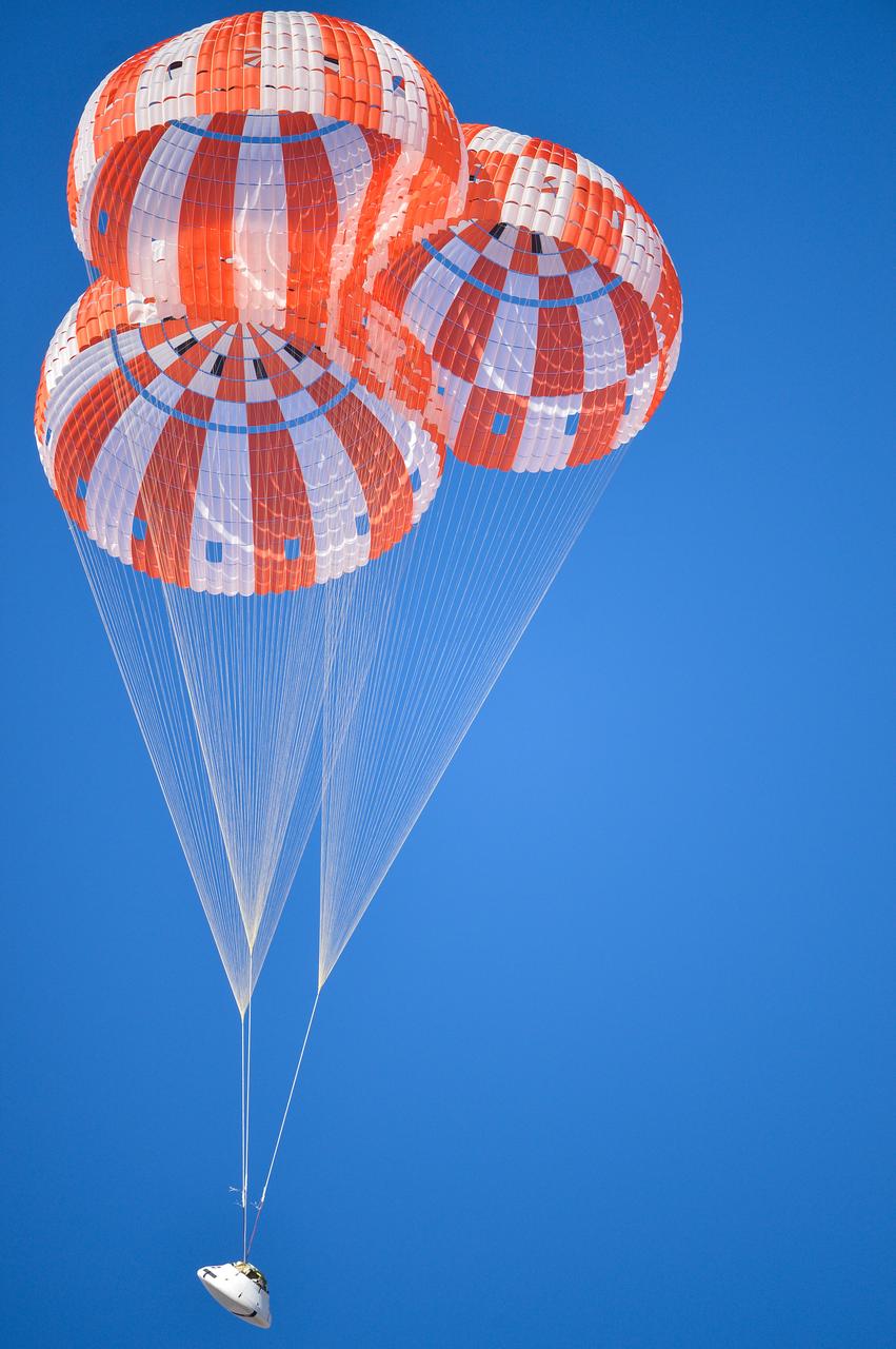 Orion’s three main orange and white parachutes help a representative model of the spacecraft descend through sky above Arizona, where NASA engineers tested the parachute system on Sept. 13, 2017 at the U.S. Army Proving Ground in Yuma. NASA is qualifying Orion’s parachutes for missions with astronauts.. .During this test, engineers replicated a situation in which Orion must abort off the Space Launch System rocket and bypasses part of its normal parachute deployment sequence that typically helps the spacecraft slow down during its descent to Earth after deep space missions. The capsule was dropped out of a C-17 aircraft at more than 4.7 miles in altitude and allowed to free fall for 20 seconds, longer than ever before, to produce high aerodynamic pressure before only its pilot and main parachutes were deployed, testing whether they could perform as expected under extreme loads. Orion’s full parachute system includes 11 total parachutes -- three forward bay cover parachutes and two drogue parachutes, along with three pilot parachutes that help pull out the spacecraft’s three mains.