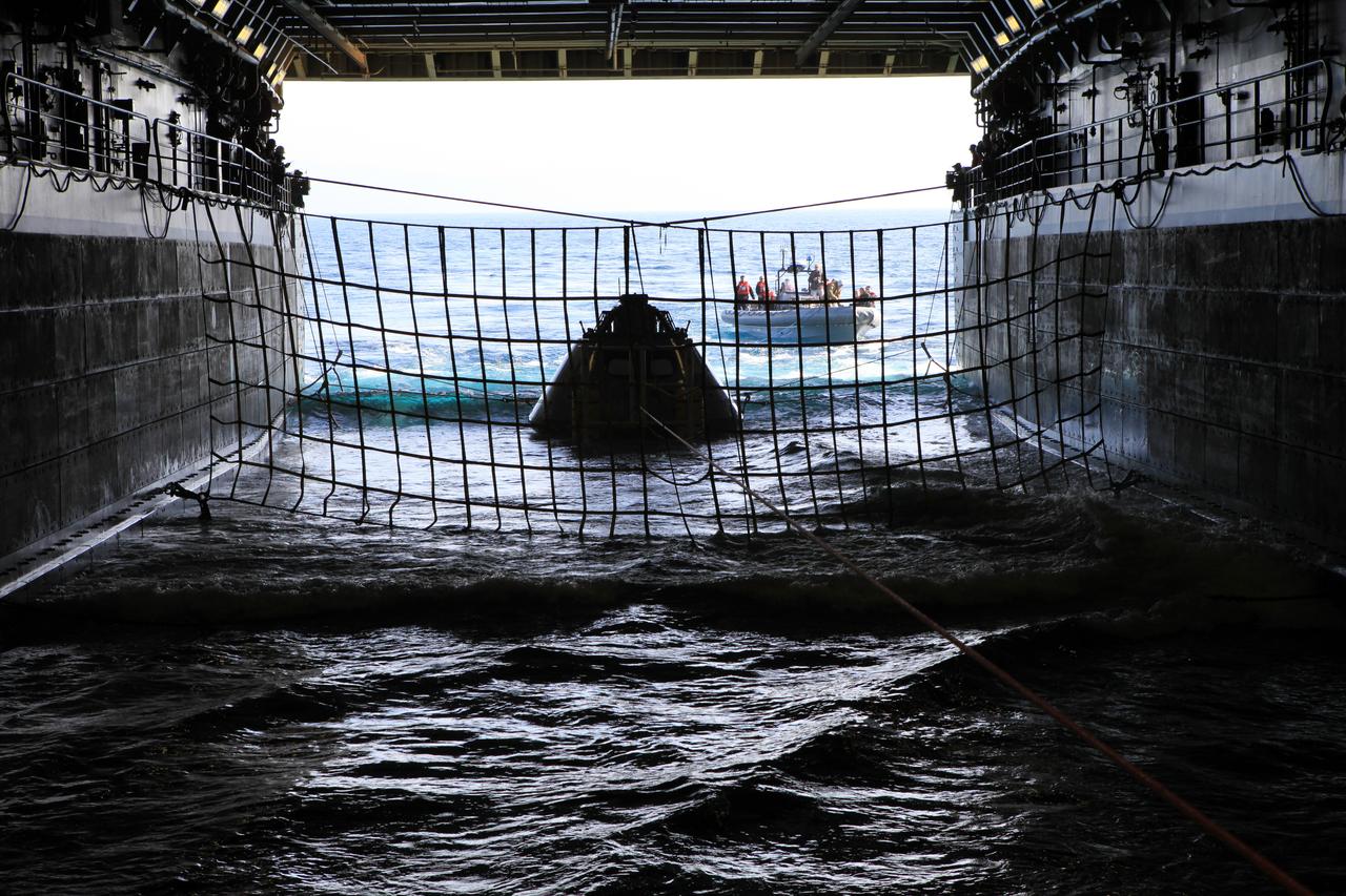 As part of Underway Recovery Test 6 on Jan. 18, 2018, the Orion test article is pulled in by a winch line at the rear of the USS Anchorage’s well deck that brings the capsule into the ship, along with four manned LLAMAs (Line Load Attenuation Mechanism Assembly) that control the capsule’s side-to-side movement and a tending line attached to a rigid hull inflatable boat for controlling Orion’s movement behind the ship. The testing with Kennedy Space Center's NASA Recovery Team and the U.S. Navy will provide important data that is being used to improve recovery procedures and hardware ahead of Orion's next flight, Artemis I, when it splashes down in the Pacific Ocean.