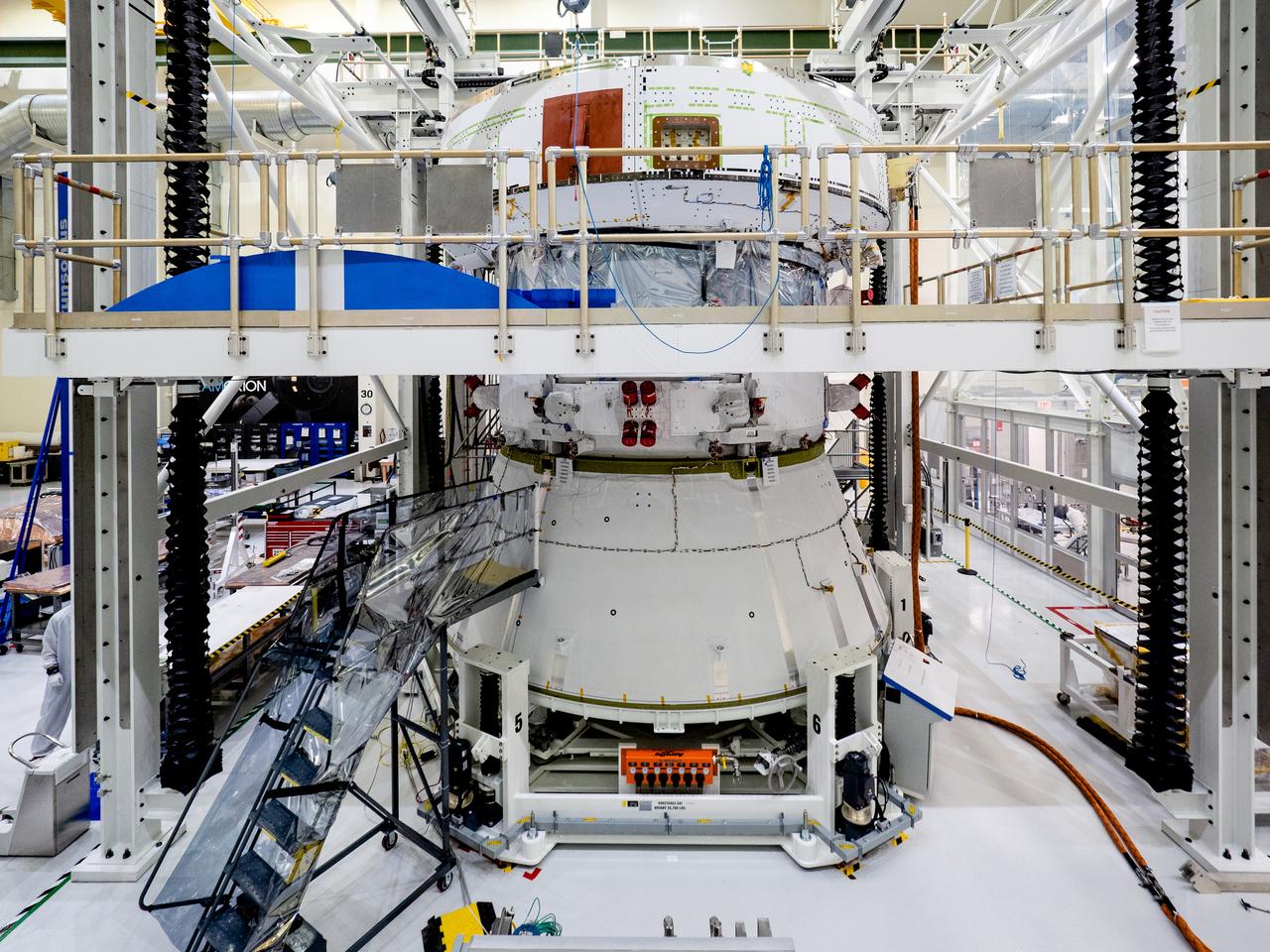 On April 29, Orion’s service module, shown here on May 2, 2019, moved to the lift station inside the assembly bay for installation and fastening of systems in preparation for Direct Field Acoustics Test (DFAT). The service module will move down to the east end of the bay next week where it will be surrounded with speakers and exposed to the acoustic level that will be experienced in space.