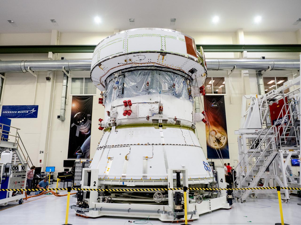On April 29, Orion’s Service Module, shown here on May 3, 2019, moved to the lift station inside the assembly bay for installation and fastening of systems in preparation for Direct Field Acoustics Test (DFAT). The Service Module will move down to the east end of the bay next week where it will be surrounded with speakers and exposed to the acoustic level that will be experienced in space.