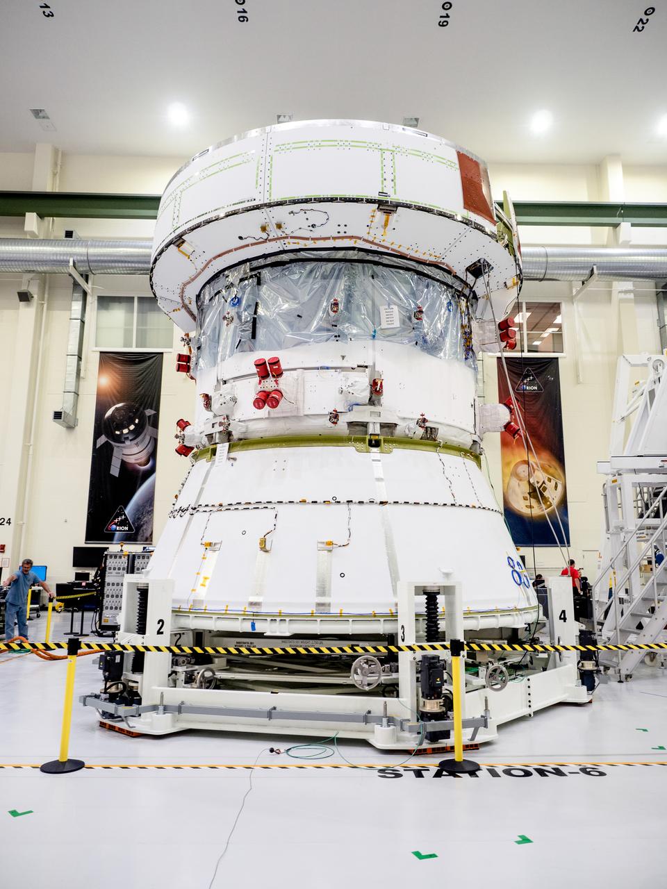 On April 29, Orion’s Service Module, shown here on May 3, 2019, moved to the lift station inside the assembly bay for installation and fastening of systems in preparation for Direct Field Acoustics Test (DFAT). The Service Module will move down to the east end of the bay next week where it will be surrounded with speakers and exposed to the acoustic level that will be experienced in space.