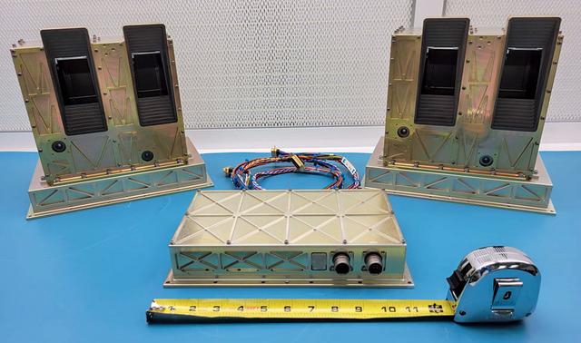 jsc2022e091372 (12/7/2022) --- The STP-H9-ECLIPSE flight hardware is shown prior to its delivery to NASA’s Johnson Space Center in March 2022. The box on the upper left in the image is the Cross-track Scanner (CTS), which views beneath the ISS and produces maps of the airglow emission. The sensor on the upper right is the Aft Limb-Scanner (ALS), which makes images of the ionospheric airglow behind the ISS in its orbit plane. The blackened rectangular structures on the boxes are the sunshade baffles around the openings to the SUVM mirrors, which are at the center of the baffles. The box near the bottom center is the Mission Operations Electronics (MOE), which controls the instruments and accepts commands from the ISS and relays data back to the ISS during the mission. The measuring tape in the image shows the size of the MOE box as approximately 11 inches wide. Image courtesy of the Naval Research Laboratory.