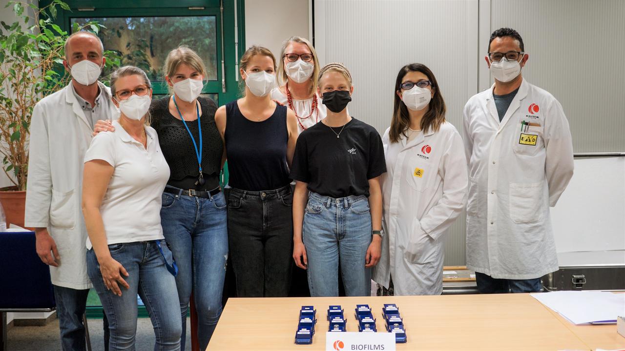 jsc2023e010180 (5/20/2022) --- This is a group picture of the DLR, ESA, and Kayser Italia teams after successful integration of the ESA-Biofilms experiment for its second launch in 2022. The assembled hardware is in the front on the table. The blue experiment containers were later integrated by ESA astronaut Samantha Cristoforetti into the two KUBIK incubators inside the Columbus laboratory aboard the International Space Station. The ESA-Biofilms investigation studies bacterial biofilm formation and antimicrobial properties of different metal surfaces under spaceflight conditions in altered gravity. Image courtesy of DLR, CC BY-NC-ND 3.0.