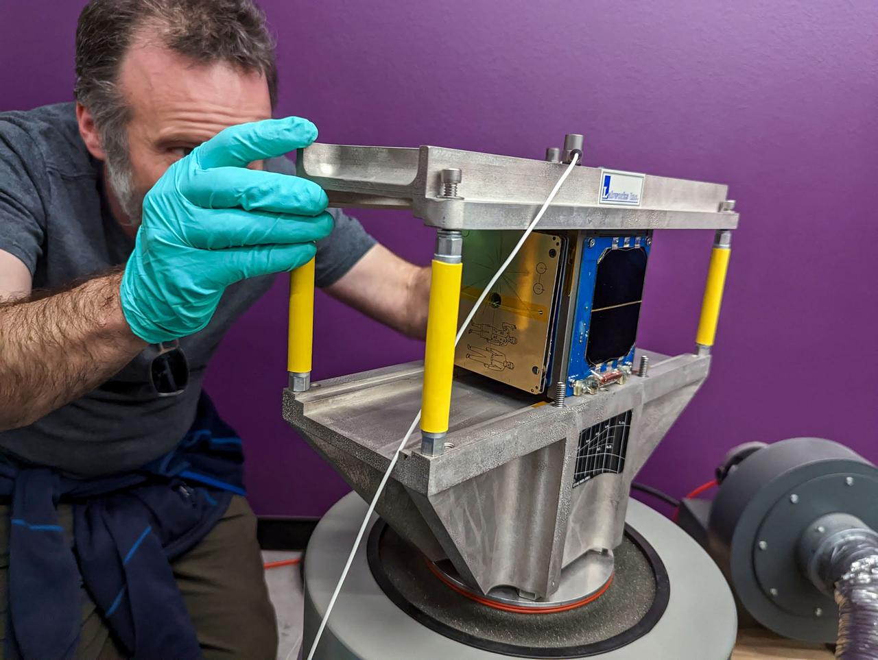 jsc2023e010186 (12/13/2022) --- Professor Danny Jacobs inspects the LightCube inside the Random Vibration Test Fixture. Image courtesy of Jaime Sanchez de la Vega.