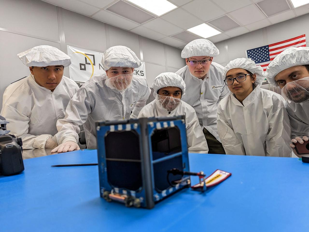 jsc2023e010188 (12/13/2022) --- LightCube team holds a signed Nanoracks CubeSat Deployer panel following integration of the LightCube CubeSat. From back to front and from left to right: Jaime Sanchez de la Vega, Raymond Barakat, Chandler Hutchens, Christopher McCormick, David Ordaz Perez, Ashley Lepham, Sam Cherian. Image courtesy of Sam Cherian.