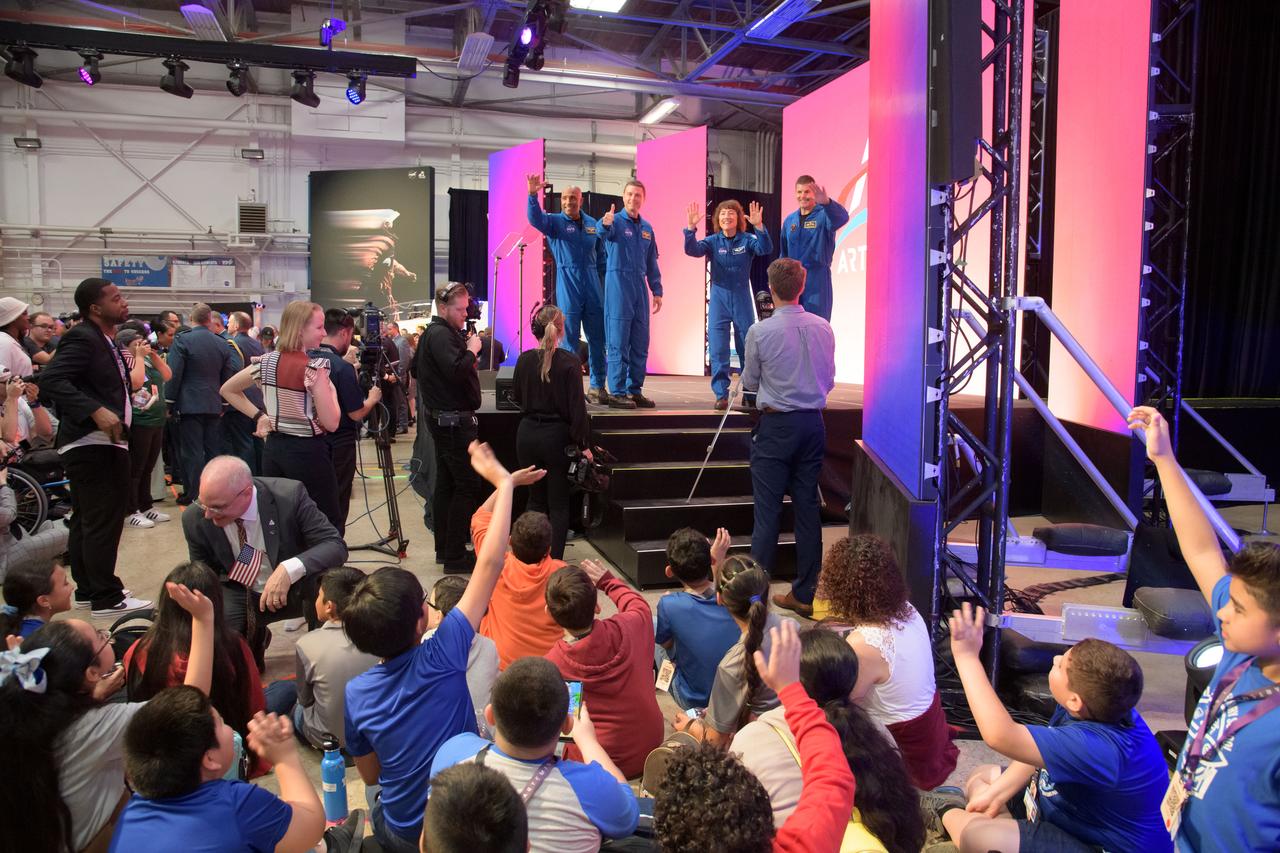 jsc2023e017091 (April 3, 2023) -- The Artemis II crew, comprised of NASA astronauts Commander Reid Wiseman, Pilot Victor Glover, and Mission Specialist Christina Koch and Canadian Space Agency astronaut Mission Specialist Jeremy Hansen, wave to a group of students from Houston’s Davila Elementary and Wesley Elementary schools during a Monday, April 3, 2023, crew announcement news conference at Ellington Field near NASA’s Johnson Space Center. The four astronauts will venture around the Moon on Artemis II, the first crewed mission on NASA’s path to establishing a long-term presence at the Moon for science and exploration through Artemis.
