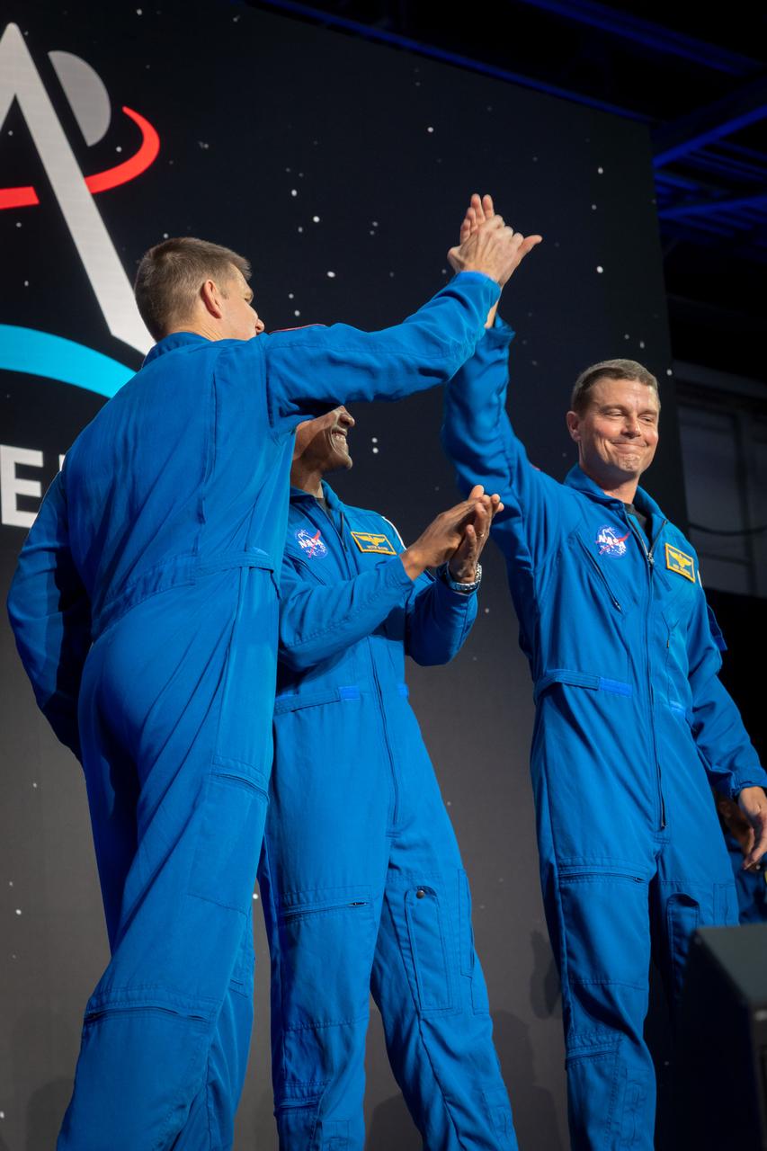 jsc2023e017440 (April 3, 2023) -- Three members of the Artemis II crew are seen on stage after being announced during a Monday, April 3, 2023, news conference at Ellington Field near NASA’s Johnson Space Center in Houston. The crew is comprised of Commander Reid Wiseman, Pilot Victor Glover, and Mission Specialists Christina Koch and Jeremy Hansen. The four astronauts will venture around the Moon on Artemis II, the first crewed mission on NASA’s path to establishing a long-term presence at the Moon for science and exploration through Artemis. From left, CSA (Canadian Space Agency) astronaut Mission Specialist Jeremy Hansen, and NASA astronauts Pilot Victor Glover and Commander Reid Wiseman.