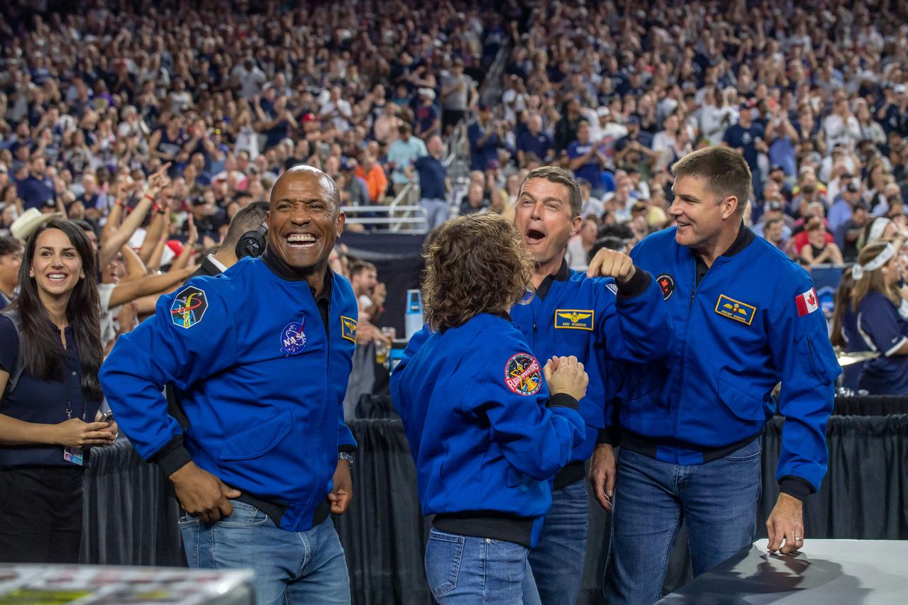 jsc2023e018321 (April 3, 2023) – The Artemis II crew cheers with the crowd while attending the NCAA Men’s Final Four national championship game at NRG Stadium in Houston. The crew is comprised of Commander Reid Wiseman, Pilot Victor Glover, and Mission Specialists Christina Koch and Jeremy Hansen. The four astronauts will venture around the Moon on Artemis II, the first crewed mission on NASA’s path to establishing a long-term presence at the Moon for science and exploration through Artemis. From left: NASA astronauts Artemis II Pilot Victor Glover, Mission Specialist Christina Koch, and Commander Reid Wiseman, and CSA (Canadian Space Agency) astronaut Mission Specialist Jeremy Hansen.