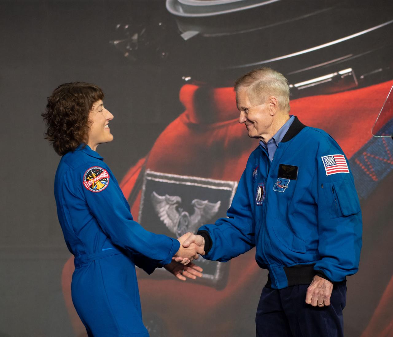 jsc2023e018404 (April 3, 2023) -- NASA astronaut Christina Koch shakes the hand of NASA Administrator Bill Nelson after being announced as one of four members of the Artemis II during a Monday, April 3, 2023, news conference at Ellington Field near NASA’s Johnson Space Center in Houston. The crew is comprised of Commander Reid Wiseman, Pilot Victor Glover, and Mission Specialists Christina Koch and Jeremy Hansen. The four astronauts will venture around the Moon on Artemis II, the first crewed mission on NASA’s path to establishing a long-term presence at the Moon for science and exploration through Artemis.