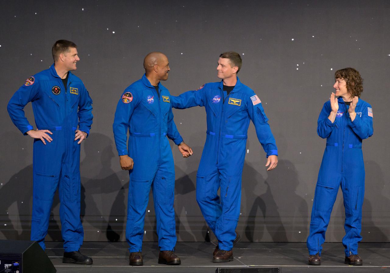 jsc2023e018440 (April 3, 2023) -- The Artemis II crew is seen on stage after being announced during a Monday, April 3, 2023, news conference at Ellington Field near NASA’s Johnson Space Center in Houston. From left: CSA (Canadian Space Agency) astronaut Mission Specialist Jeremy Hansen, and NASA astronauts Pilot Victor Glover, Commander Reid Wiseman, and Mission Specialist Christina Koch. The four astronauts will venture around the Moon on Artemis II, the first crewed mission on NASA’s path to establishing a long-term presence at the Moon for science and exploration through Artemis.