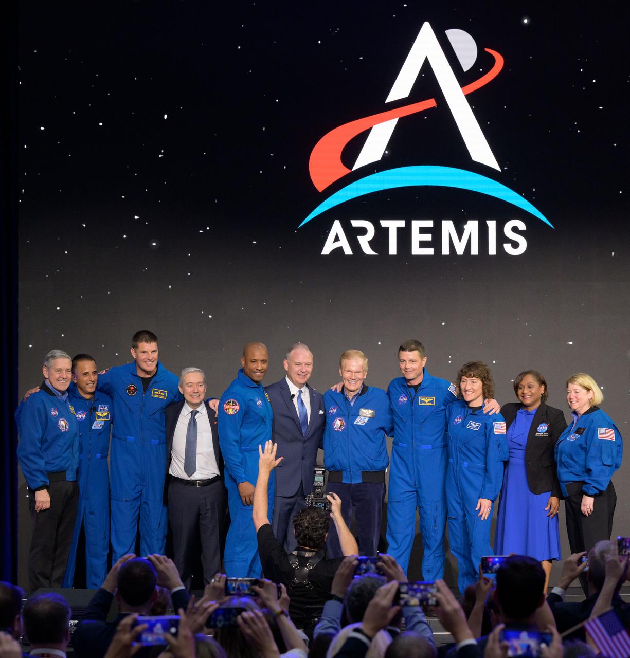 jsc2023e018442 (April 3, 2023) -- The Artemis II crew is seen on stage with NASA and Canadian leadership after being announced during a Monday, April 3, 2023, news conference at Ellington Field near NASA’s Johnson Space Center in Houston. The crew is comprised of Commander Reid Wiseman, Pilot Victor Glover, and Mission Specialists Christina Koch and Jeremy Hansen. The four astronauts will venture around the Moon on Artemis II, the first crewed mission on NASA’s path to establishing a long-term presence at the Moon for science and exploration through Artemis. From left: NASA Associate Administrator Bob Cabana, NASA Chief Astronaut Joe Acaba, CSA Astronaut and Artemis II Mission Specialist Jeremy Hansen, The Honorable François-Philippe Champagne, the minister responsible for the Canadian Space Agency, NASA Astronaut Artemis II Pilot Victor Glover, NASA Flight Operations Director Norm Knight, NASA Administrator Bill Nelson, NASA Astronaut Artemis II Commander Reid Wiseman, NASA Astronaut Artemis II Mission Specialist Christina Koch, NASA Johnson Space Center Director Vanessa Wyche, NASA Deputy Administrator Pam Melroy.