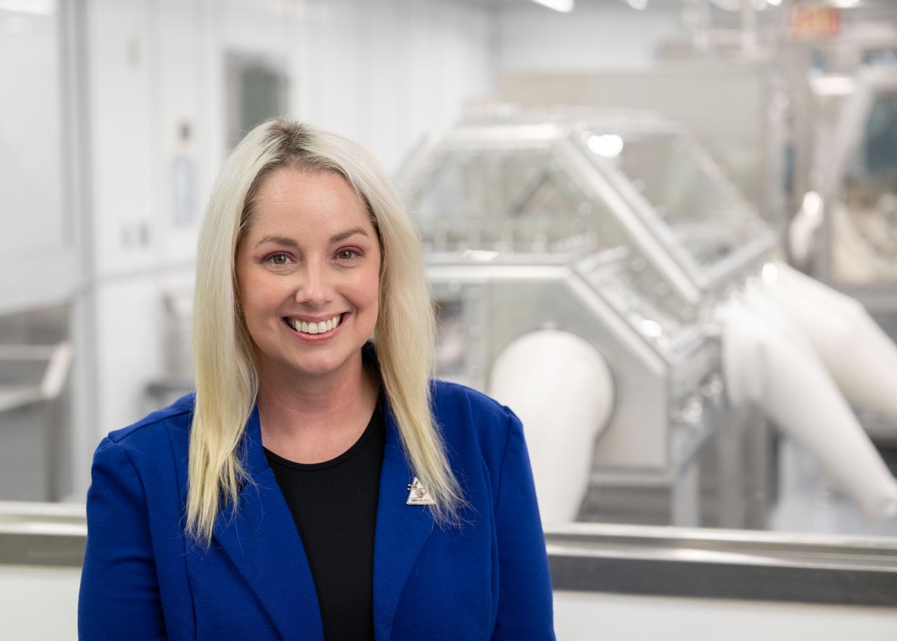 Portrait of Rachel Funk, OSIRIS-REx astromaterials processor from the Astromaterials Research and Exploration Science (ARES) division at NASA's Johnson Space Center in Houston. Funk is seen in front of the OSIRIS-REx cleanroom at Johnson. Credit: NASA/James Blair 