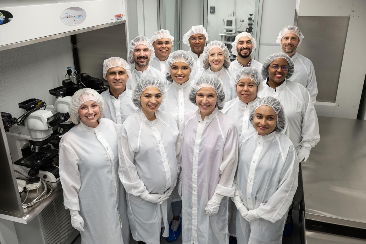 The OSIRIS-REx curation integrated processing and engineering team in the H2-OREx Staging area just outside the pristine OSIRIS-REx laboratory. Left-to-right and front-to-back: Rachel Funk, Carla Gonzalez, Nicole Lunning, Jannatul Ferdous, Neftali Hernandez, Mari Montoya, Melissa Rodriguez, Curtis Calva, Julia Plummer, Kimberly Allums-Spencer, Gabriel Lugo, Christopher Snead, Sal Martinez, and Wayland Connelly.