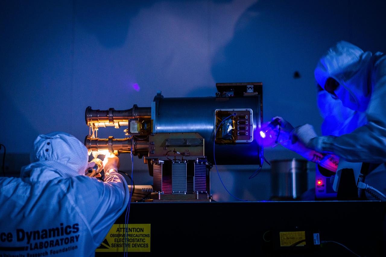 jsc2023e055876 (6/3/2021) --- Space Dynamics Laboratory (SDL) engineering and safety mission assurance personnel perform a cleanliness check with a black light on the The Atmospheric Waves Experiment (AWE) engineering model at SDL facilities on Utah State University’s Innovation Campus. Image courtesy of SDL/Allison Bills.