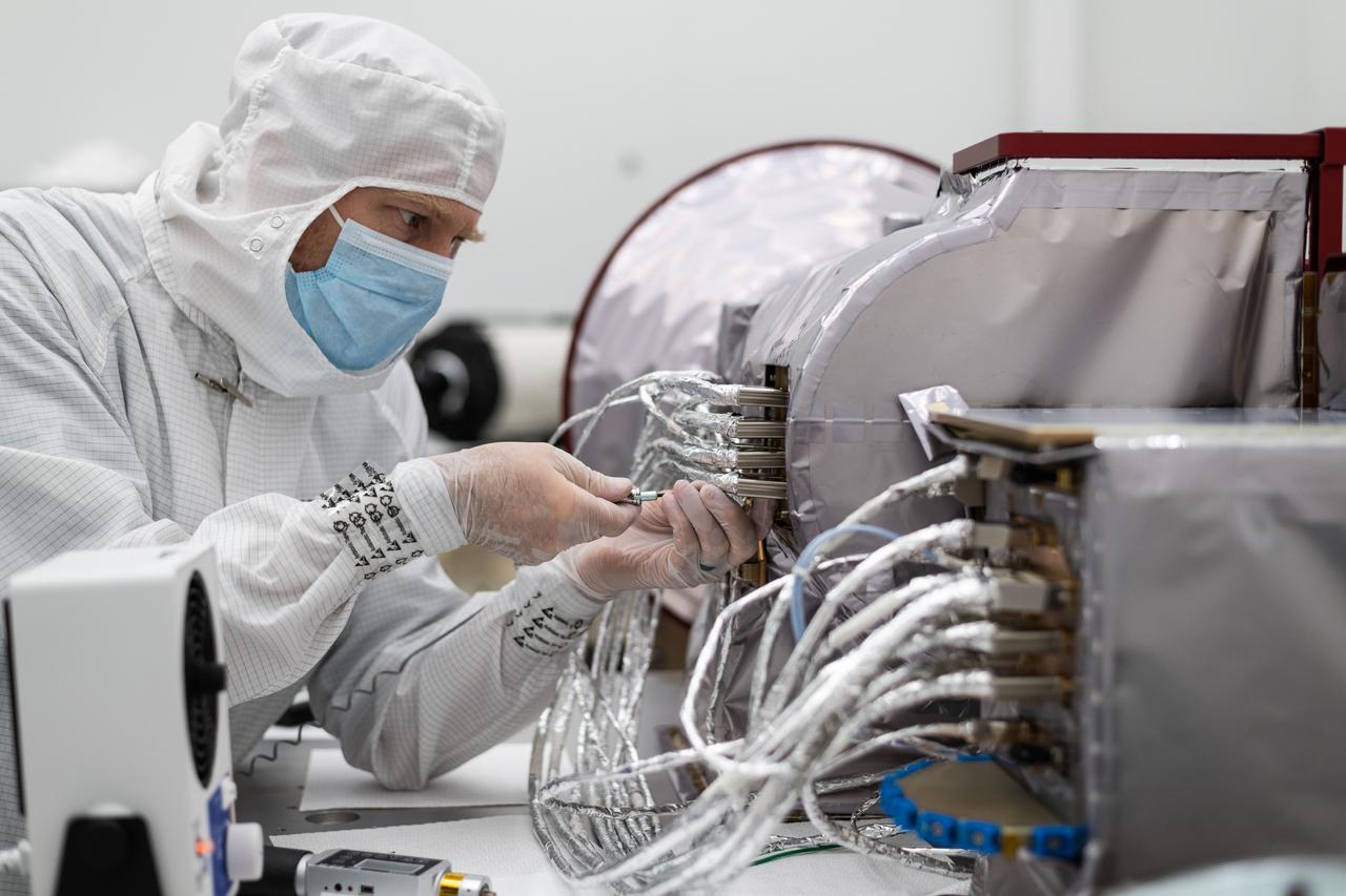 jsc2023e055880 (11/21/2022) --- Space Dynamics Laboratory (SDL) employee installs the cable harness installation on the Opto-Mechanical Assembly, with the Instrument Electronics Box in the foreground SDL facilities on Utah State University’s Innovation Campus. Image courtesy of SDL/Allison Bills.