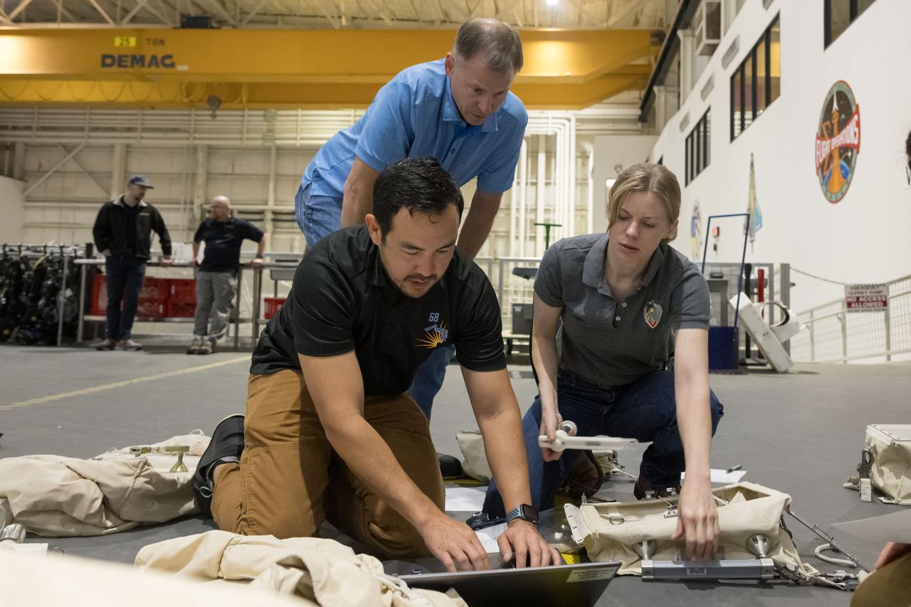 jsc2023e071510 (Nov. 6, 2023) --- NASA astronauts Nick Hague and Zena Cardman, assisted by a technician (foreground), check out spacewalking hardware at the Neutral Buoyancy Laboratory at NASA's Johnson Space Center in Houston, Texas, for the SpaceX Crew-9 mission to the International Space Station. Credit: NASA/Bill Stafford