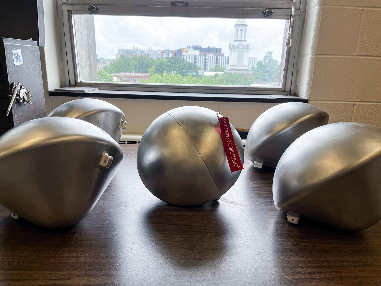 jsc2024e005968 (1/122024) --- The five Kentucky Re-Entry Universal Payload System (KRUPS) capsules of the KREPE-2 mission are pictured on the ground, encapsulated in the ISS-KREM shell. Thermal Protection Systems (TPS) technology uses three capsules outfitted with different heat shield materials and a variety of sensors to obtain data on actual reentry conditions. KREPE-2 tests new heat shields from NASA as well as a heat shield manufactured entirely at the University of Kentucky. Image courtesy of the University of Kentucky.