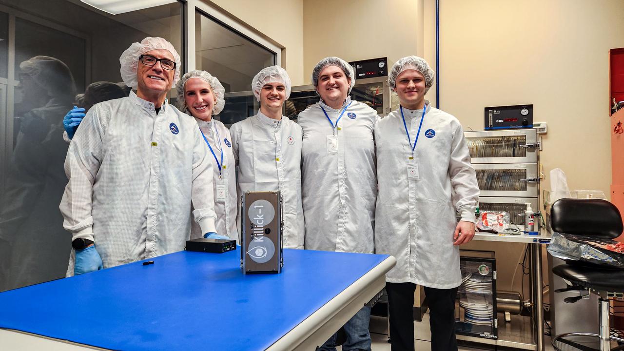 jsc2024e016245 (11/27/2023) --- The Nanoracks-Killick-1 Satellite Integration Team in the Canadian Space Agency (CSA) clean room with the Killick-1 satellite (foreground). From left to right – Desmond Power (Co-Principal Investigator), Victoria Vaters (Mechanical Engineering Student), Cameron King (Computer Engineering Student), Matthew Fewer (Computer Engineering Student), Daniel Dolomount (computer Engineering Student). Nanoracks-Killick-1 is a CubeSat that measures sea ice parameters using Global Navigation Satellite System (GNSS) reflectometry or reflected signals. Image courtesy of C-CORE and Memorial University.