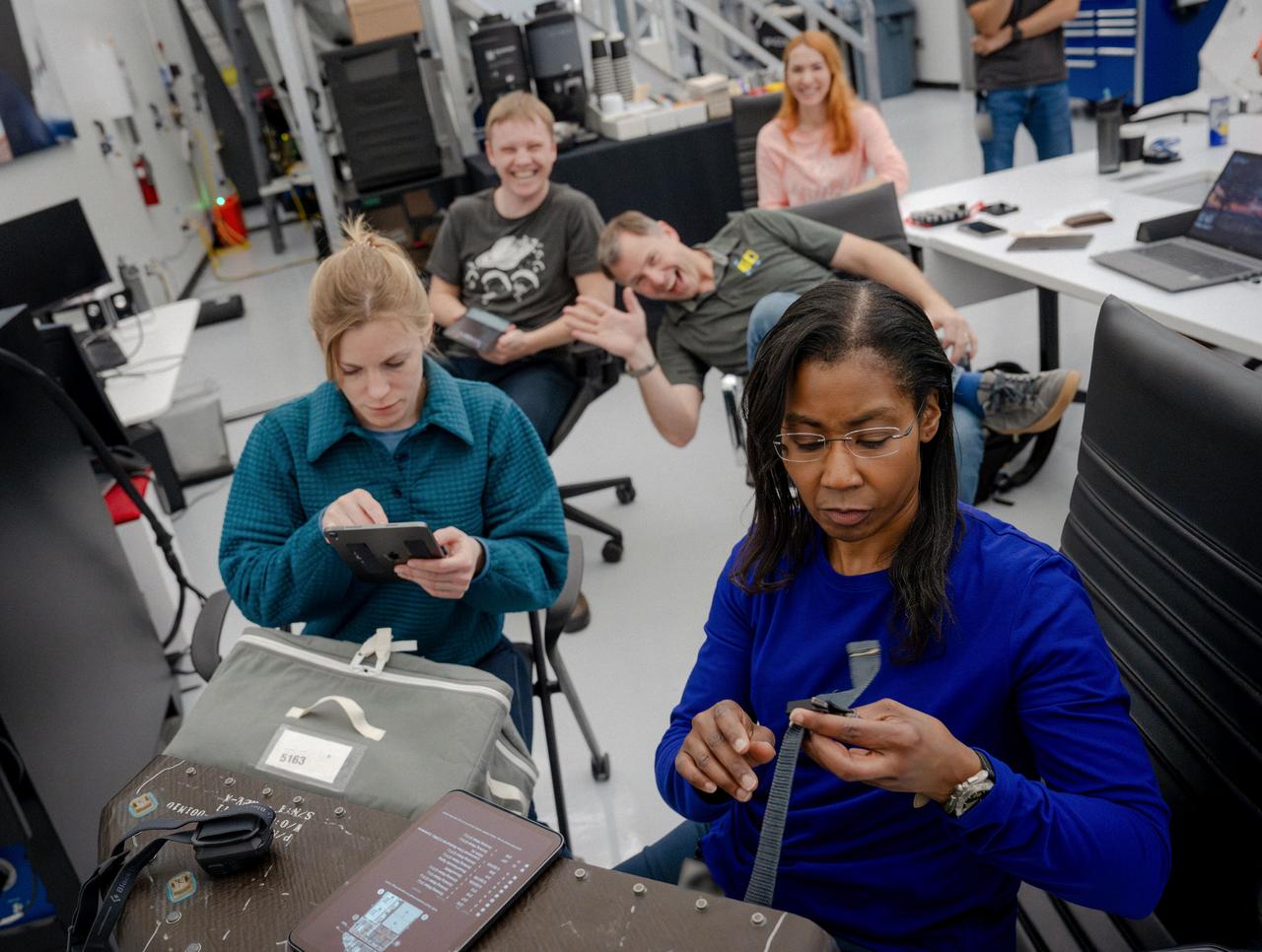 jsc2024e024939 (March 1, 2024) --- NASA’s SpaceX Crew-9 members Mission Specialist Aleksandr Gorbunov and Pilot Nick Hague smile big for the camera while Commander Zena Cardman and Mission Specialist Stephanie Wilson train on how to route straps and buckles around various bags that need to be stored in the Dragon spacecraft. Credit: SpaceX