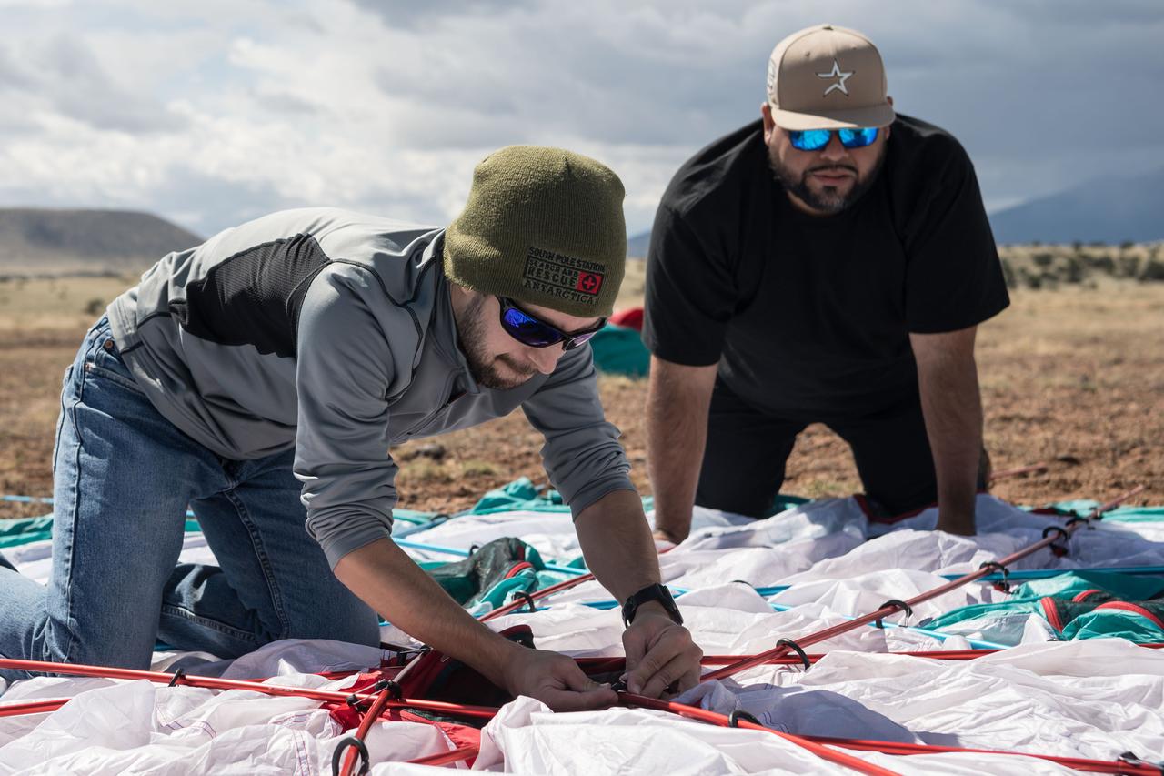 Spacesuit engineers Zach Tejral (left) and Joel Alvarado (right) work to set up the base camp for the Joint Extravehicular Activity and Human Surface Mobility Test Team Field Test 5 in the San Francisco Volcanic Field in Northern Arizona on May 11, 2024.  Credit: NASA/Josh Valcarcel 