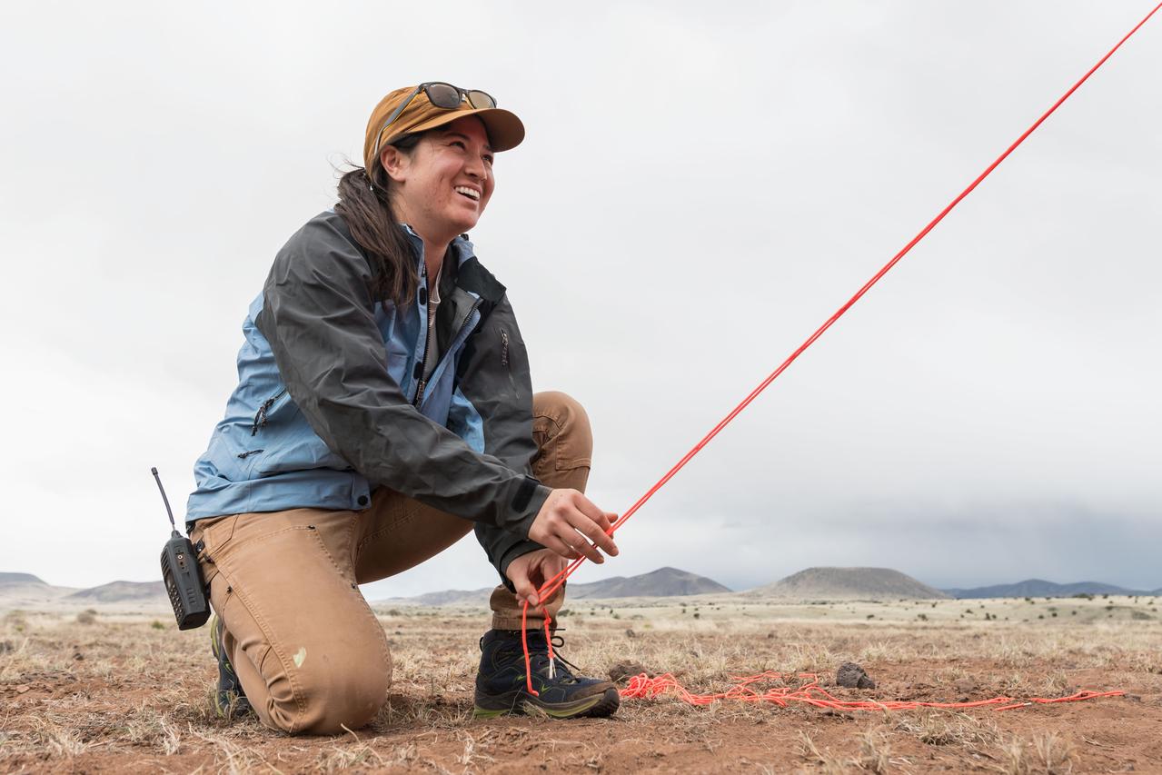 Test deputy field manager Angela Garcia ties down a tent that will serve as the base camp for the Joint Extravehicular Activity and Human Surface Mobility Test Team Field Test 5 (JETT5) in the San Francisco Volcanic Field in Northern Arizona on May 11, 2024.  Credit: NASA/Josh Valcarcel 