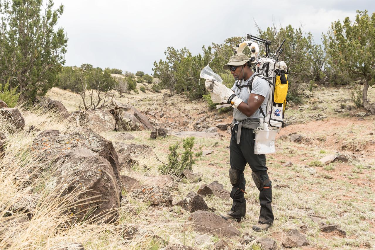 NASA astronaut Andre Douglas examines a geology sample he collected during a simulated moonwalk in the San Francisco Volcanic Field in Northern Arizona on May 14, 2024.  Credit: NASA/Josh Valcarcel 
