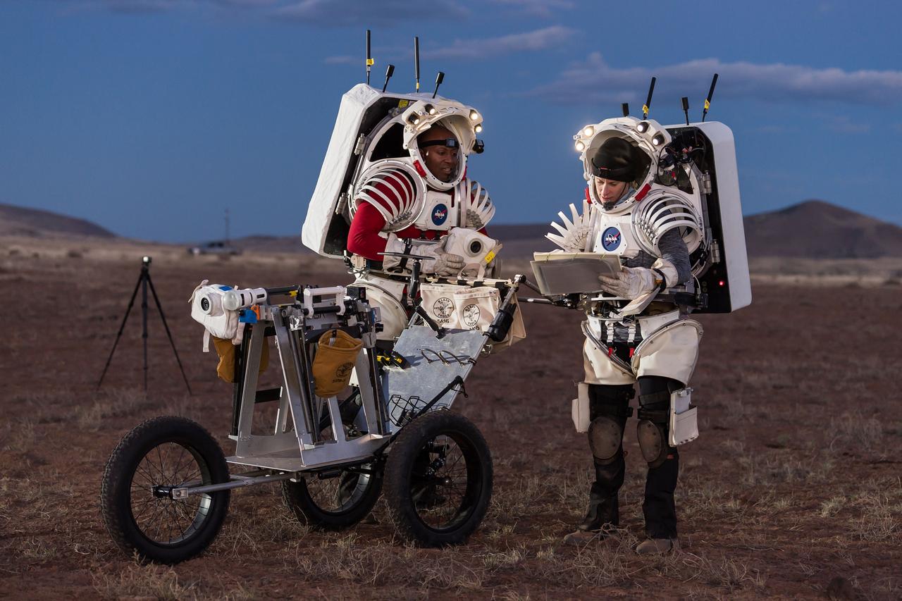 NASA astronauts Andre Douglas, left, and Kate Rubins review procedures during a nighttime simulated moonwalk in the San Francisco Volcanic Field in Northern Arizona on May 16, 2024.  Credit: NASA/Josh Valcarcel 
