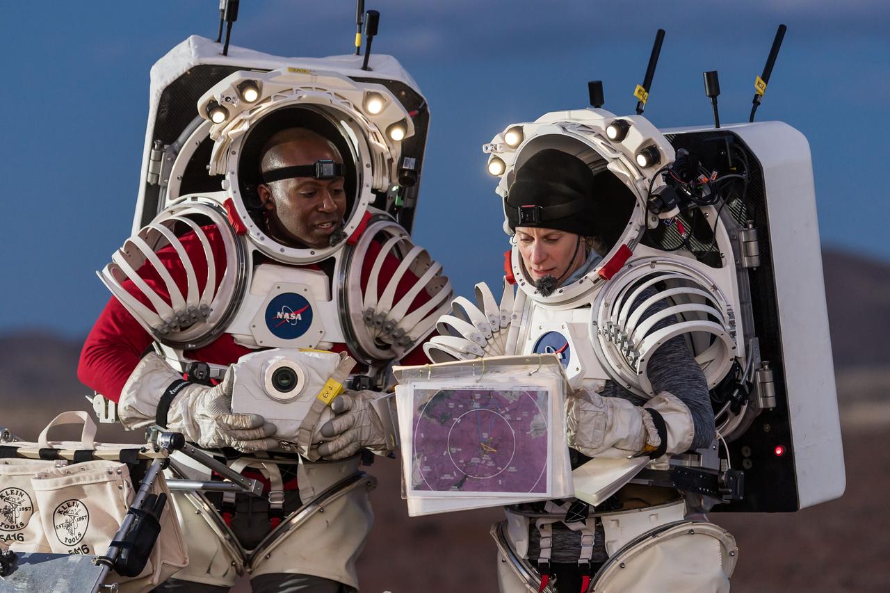 NASA astronauts Andre Douglas, left, and Kate Rubins review traverse plans during a¬¬ nighttime simulated moonwalk in the San Francisco Volcanic Field in Northern Arizona on May 16, 2024.  Credit: NASA/Josh Valcarcel 
