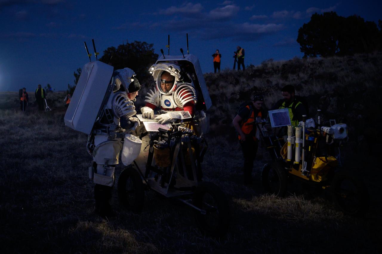 NASA astronauts Kate Rubins, left, and Andre Douglas look at a map that shows their traverse route during a nighttime simulated moonwalk in the San Francisco Volcanic Field in Northern Arizona on May 16, 2024.  Credit: NASA/Josh Valcarcel 