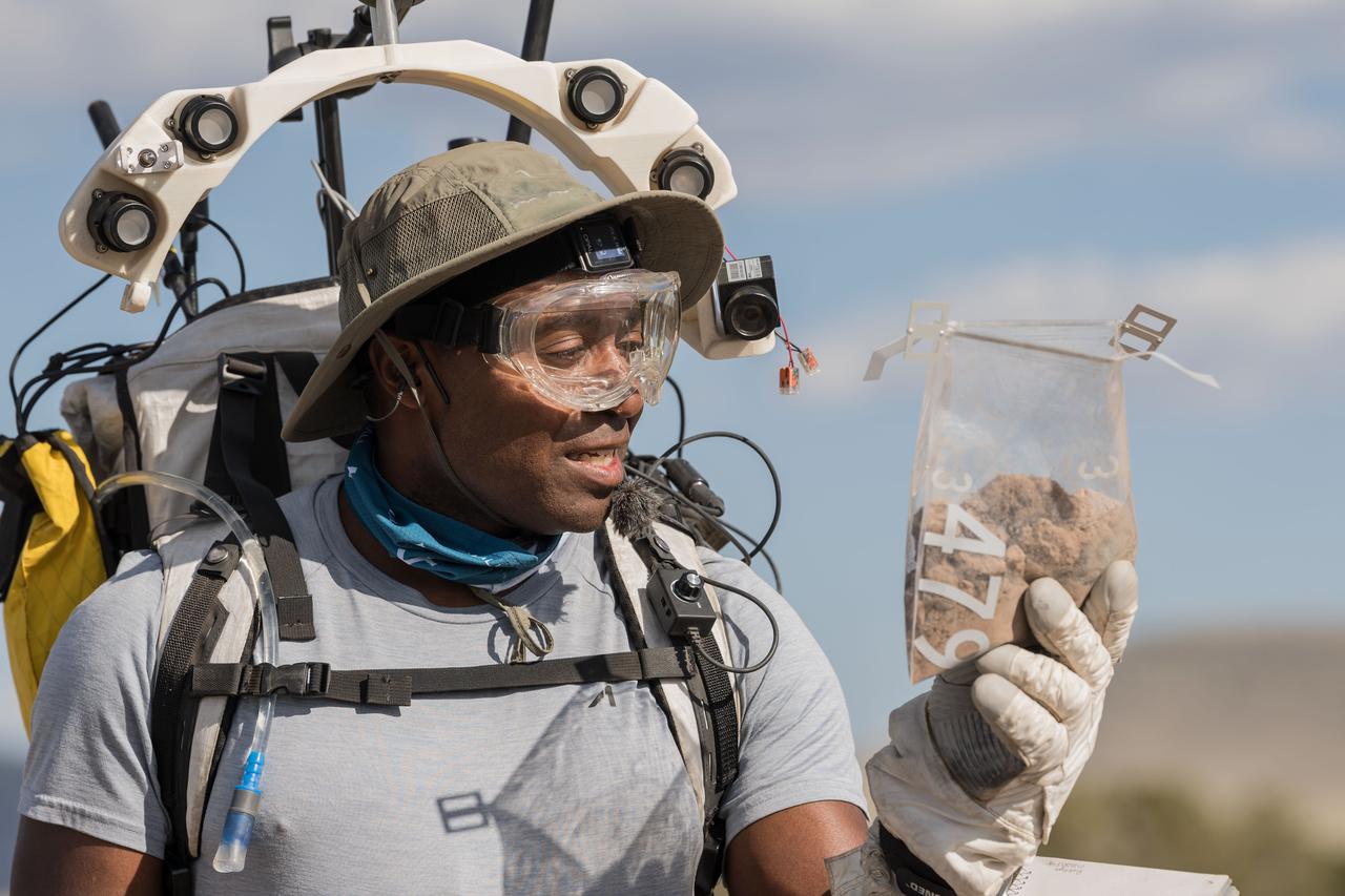 NASA astronaut Andre Douglas takes a closer look at the geologic samples he collected during a simulated moonwalk in the San Francisco Volcanic Field in Northern Arizona on May 17, 2024. Credit: NASA/Josh Valcarcel 