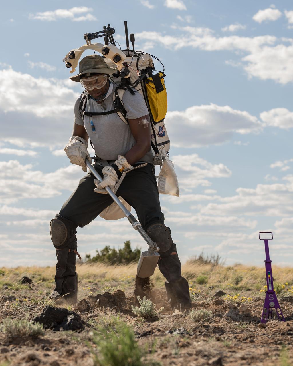 NASA astronaut Andre Douglas uses a scoop to dig into the ground to collect geologic samples during a simulated moonwalk in the San Francisco Volcanic Field in Northern Arizona on May 17, 2024. Credit: NASA/Josh Valcarcel 