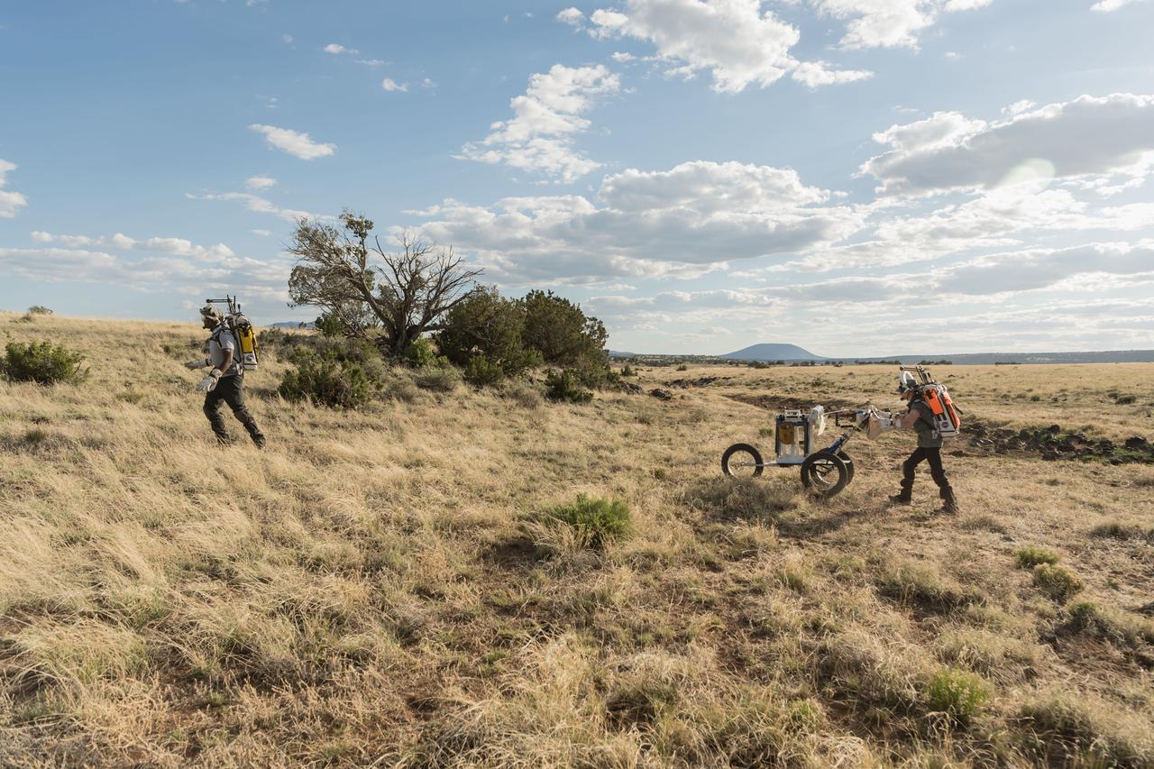 NASA astronaut Andre Douglas leads the way while NASA astronaut Kate Rubins follows behind with a lunar tool cart during a simulated moonwalk in the San Francisco Volcanic Field in Northern Arizona on May 17, 2024. Credit: NASA/Josh Valcarcel 