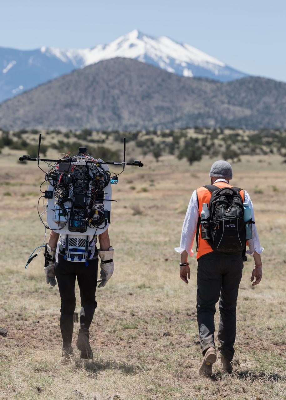 NASA astronaut Kate Rubins walks through the lunar-like landscape wearing the Joint AR (Joint Augmented Reality Visual Informatics System) display during an advanced technology run in the San Francisco Volcanic Field in Northern Arizona on May 19, 2024. The suit display features include navigation, photo capture, graphical format of consumables, procedure viewing, mission control updates, and other augmented reality cues and graphics. The team successfully tested navigation displays using data from four different data streams: GPS (Global Positioning System)/IMU (Inertial Measurement Unit), camera/IMU, LiDAR (Light Detection and Ranging), and static maps. Technology like this may be used for future Artemis missions to augment mission control communication and help guide crew back to the lunar lander. Credit: NASA/Josh Valcarcel 