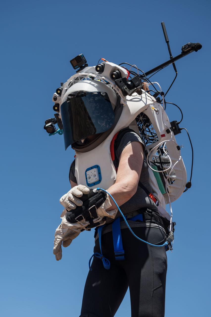 NASA astronaut Kate Rubins uses the hand controller on her wrist to display information while wearing the Joint AR (Joint Augmented Reality Visual Informatics System) display during an advanced technology run in the San Francisco Volcanic Field in Northern Arizona on May 19, 2024. The suit display features include navigation, photo capture, graphical format of consumables, procedure viewing, mission control updates, and other augmented reality cues and graphics. The team successfully tested navigation displays using data from four different data streams: GPS (Global Positioning System)/IMU (Inertial Measurement Unit), camera/IMU, LiDAR (Light Detection and Ranging), and static maps. Technology like this may be used for future Artemis missions to augment mission control communication and help guide crew back to the lunar lander. Credit: NASA/Josh Valcarcel 