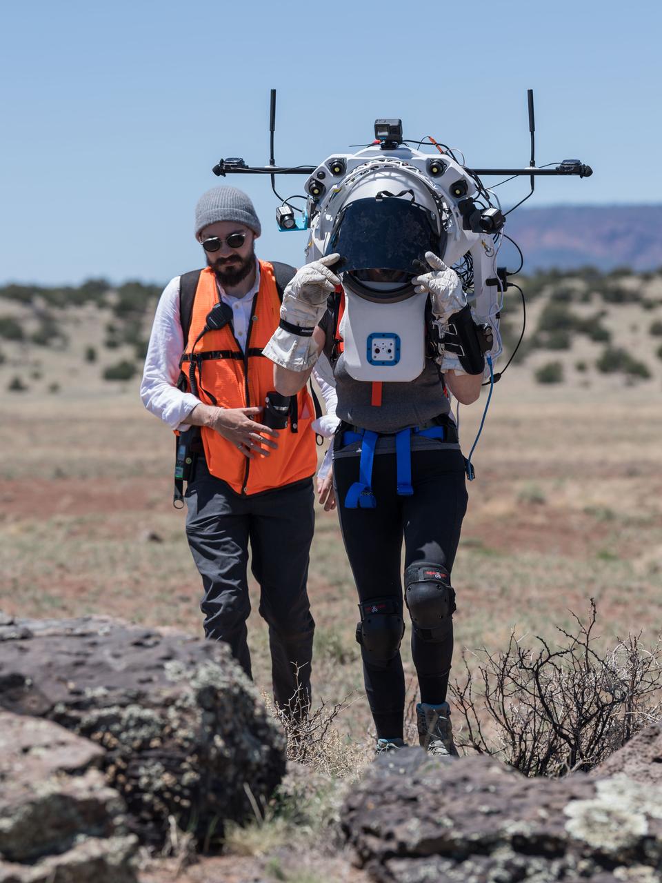 NASA astronaut Kate Rubins walks through the lunar-like landscape wearing the Joint AR (Joint Augmented Reality Visual Informatics System) display during an advanced technology run in the San Francisco Volcanic Field in Northern Arizona on May 19, 2024. The suit display features include navigation, photo capture, graphical format of consumables, procedure viewing, mission control updates, and other augmented reality cues and graphics. The team successfully tested navigation displays using data from four different data streams: GPS (Global Positioning System)/IMU (Inertial Measurement Unit), camera/IMU, LiDAR (Light Detection and Ranging), and static maps. Technology like this may be used for future Artemis missions to augment mission control communication and help guide crew back to the lunar lander. Credit: NASA/Josh Valcarcel 