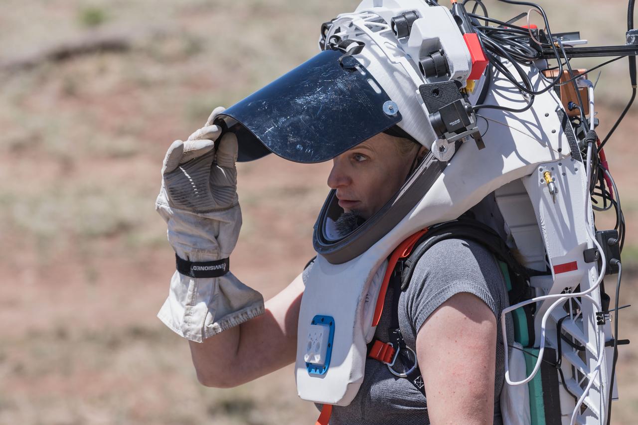 NASA astronaut Kate Rubins opens the sun visor on the Joint AR (Joint Augmented Reality Visual Informatics System) display she’s wearing during an advanced technology run in the San Francisco Volcanic Field in Northern Arizona on May 19, 2024. The suit display features include navigation, photo capture, graphical format of consumables, procedure viewing, mission control updates, and other augmented reality cues and graphics. The team successfully tested navigation displays using data from four different data streams: GPS (Global Positioning System)/IMU (Inertial Measurement Unit), camera/IMU, LiDAR (Light Detection and Ranging), and static maps. Technology like this may be used for future Artemis missions to augment mission control communication and help guide crew back to the lunar lander. Credit: NASA/Josh Valcarcel 