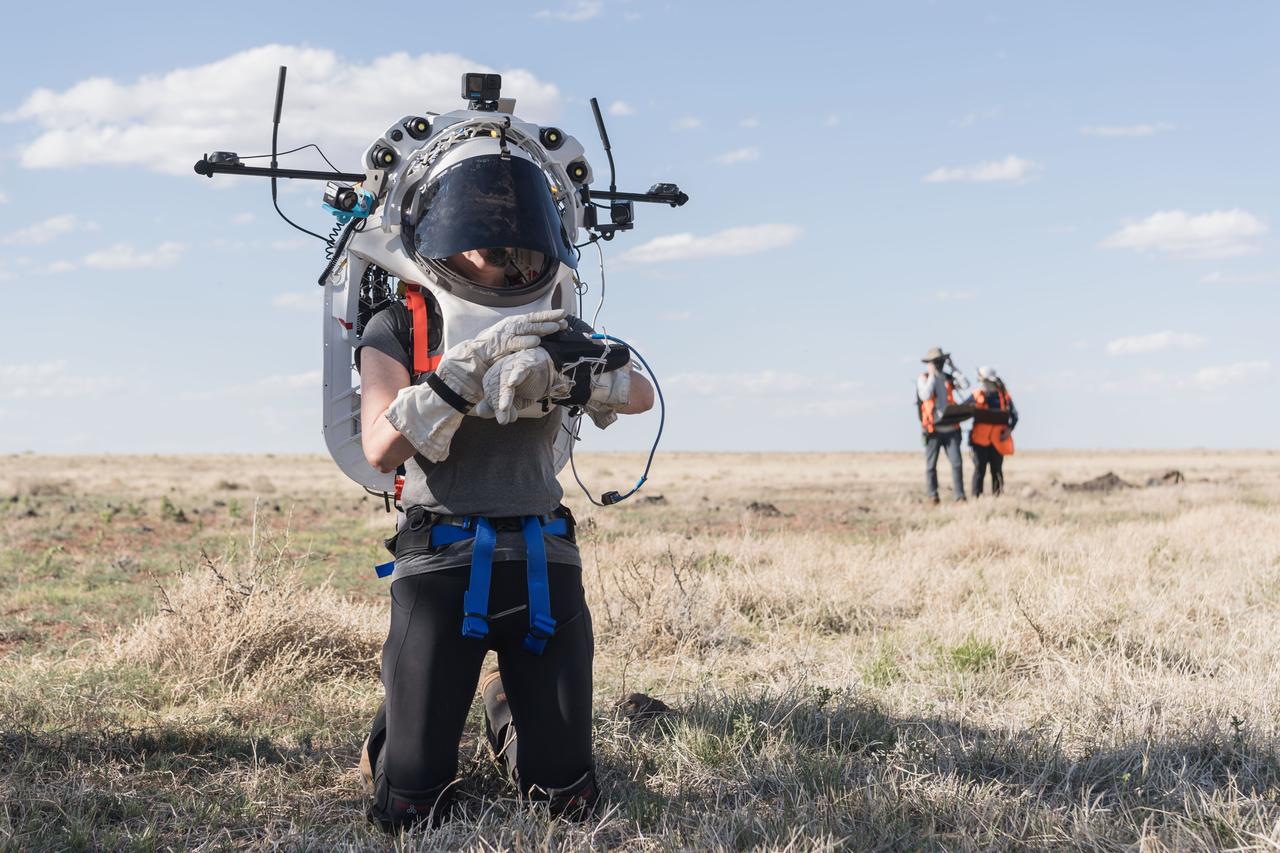 NASA astronaut Kate Rubins uses the hand controller on her wrist to display information while wearing the Joint AR (Joint Augmented Reality Visual Informatics System) display during an advanced technology run in the San Francisco Volcanic Field in Northern Arizona on May 21, 2024. The suit display features include navigation, photo capture, graphical format of consumables, procedure viewing, mission control updates, and other augmented reality cues and graphics. The team successfully tested navigation displays using data from four different data streams: GPS (Global Positioning System)/IMU (Inertial Measurement Unit), camera/IMU, LiDAR (Light Detection and Ranging), and static maps. Technology like this may be used for future Artemis missions to augment mission control communication and help guide crew back to the lunar lander. Credit: NASA/Josh Valcarcel 