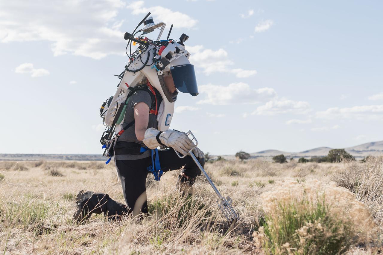 NASA astronaut Kate Rubins uses tongs to collect geologic samples while wearing the Joint AR (Joint Augmented Reality Visual Informatics System) display during an advanced technology run in the San Francisco Volcanic Field in Northern Arizona on May 21, 2024. The suit display features include navigation, photo capture, graphical format of consumables, procedure viewing, mission control updates, and other augmented reality cues and graphics. The team successfully tested navigation displays using data from four different data streams: GPS (Global Positioning System)/IMU (Inertial Measurement Unit), camera/IMU, LiDAR (Light Detection and Ranging), and static maps. Technology like this may be used for future Artemis missions to augment mission control communication and help guide crew back to the lunar lander. Credit: NASA/Josh Valcarcel 