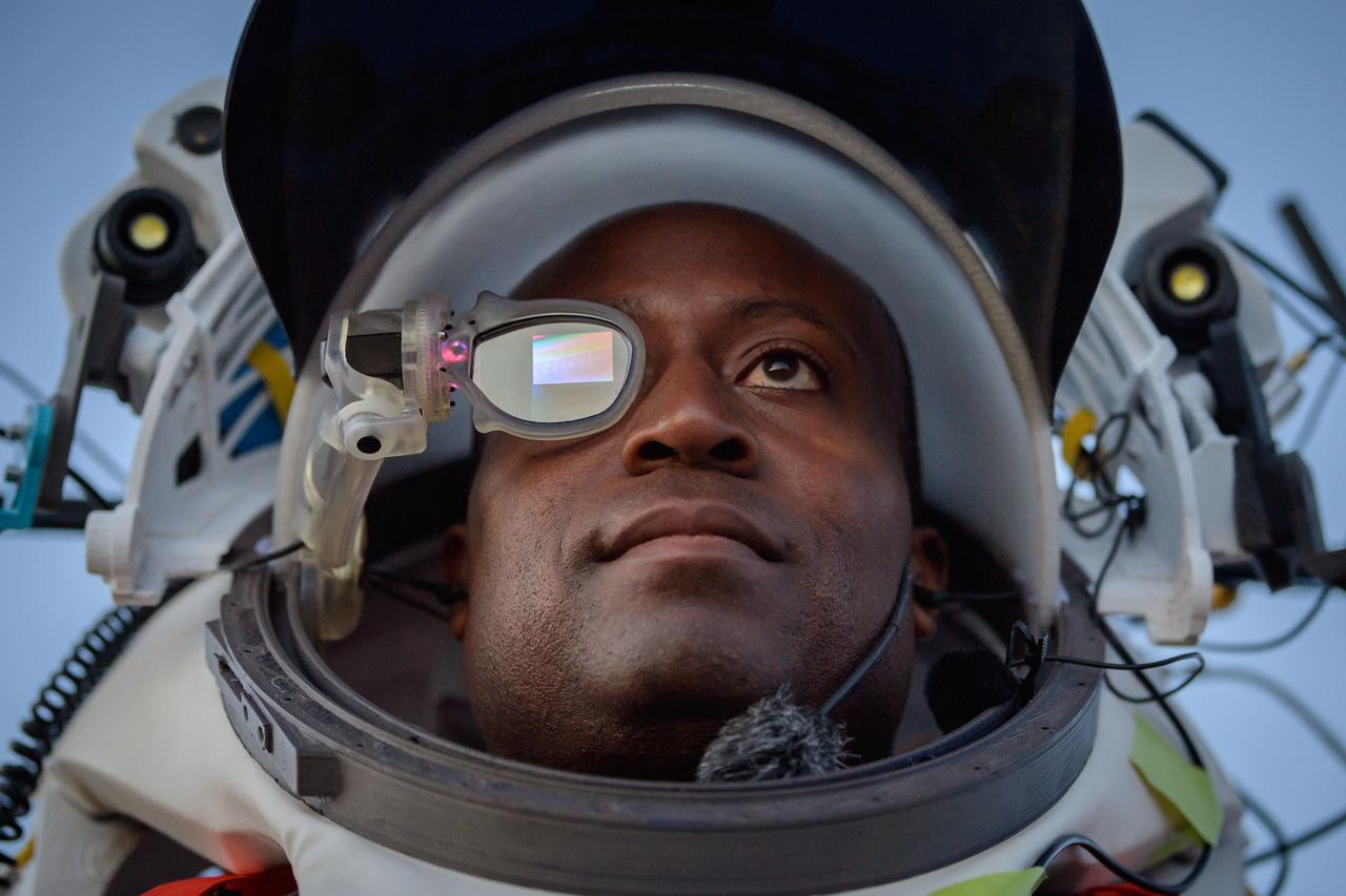 NASA astronaut Andre Douglas wears AR (Augmented Reality) display technology during an advanced technology run in the San Francisco Volcanic Field in Northern Arizona on May 21, 2024. The monocular lens consists of a pico-projector and waveguide optical element to focus an image for crew to see their real world overlaid with digital information. These unique near-eye form factors may be used to improve the usability and minimally impact the complex biomechanics of working in a pressurized suit environment. Credit: NASA/Josh Valcarcel 