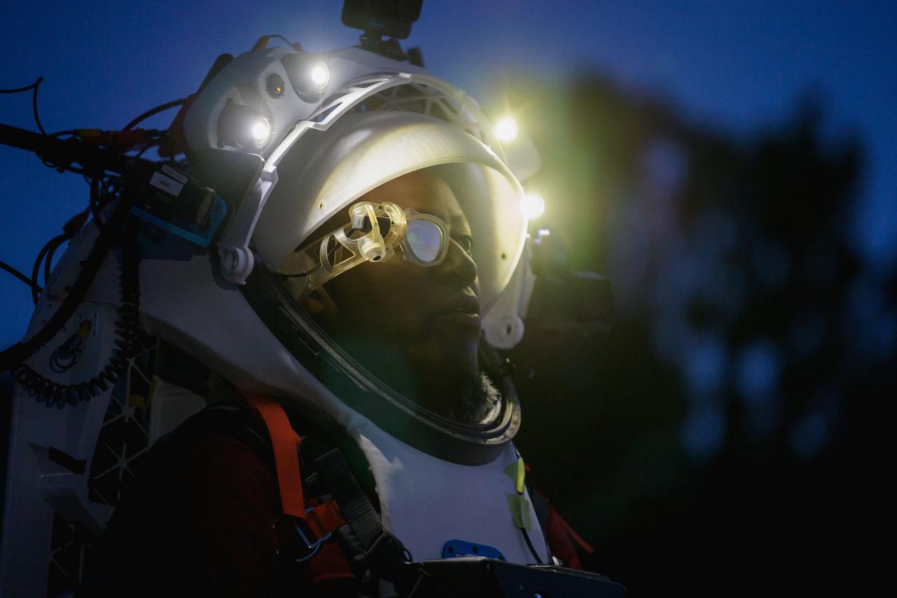 NASA astronaut Andre Douglas wears AR (Augmented Reality) display technology during a nighttime advanced technology run in the San Francisco Volcanic Field in Northern Arizona on May 21, 2024. The monocular lens consists of a pico-projector and waveguide optical element to focus an image for crew to see their real world overlaid with digital information. These unique near-eye form factors may be used to improve the usability and minimally impact the complex biomechanics of working in a pressurized suit environment. Credit: NASA/Josh Valcarcel 