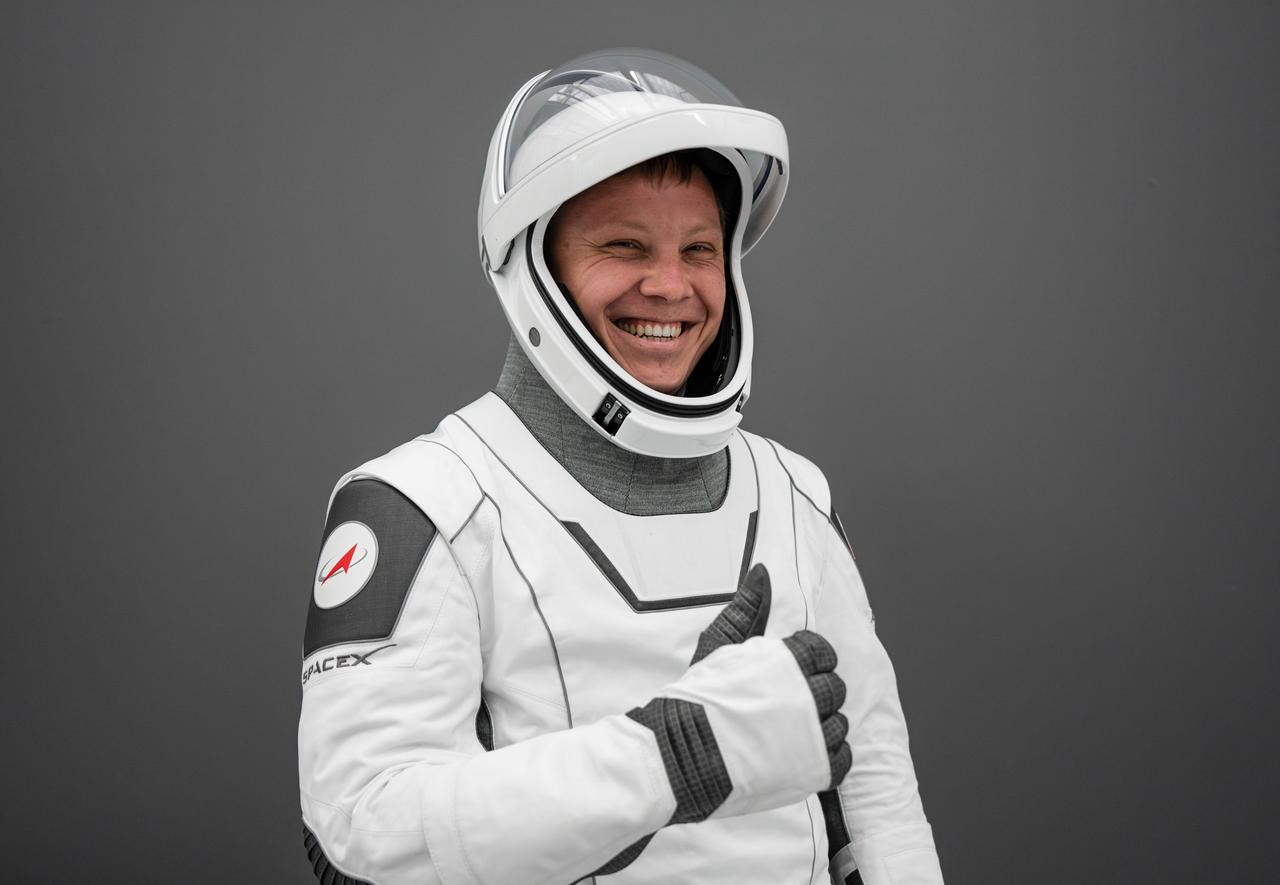 jsc2024e042505 (May 5, 2024) --- Roscosmos cosmonaut and SpaceX Crew-9 Mission Specialist Aleksandr Gorbunov gives a thumbs-up in his flight suit at SpaceX headquarters in Hawthorne, California. Credit: SpaceX