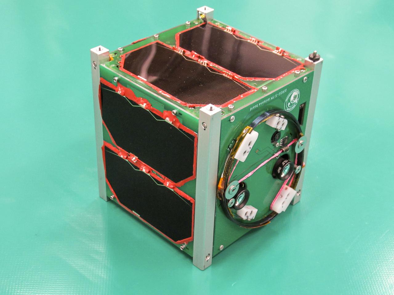 JSC2024E043924 (4/14/2025) --- The CosmoGirl-Sat CubeSat from Japan Aerospace Exploration Agency (JAXA) shows deep blue solar panels at the front of the spacecraft that power three sunken camera lenses (seen on the top of the satellite), amongst a plethora of other subsystems. CosmoGirl-Sat is developed by the Cosmo Women’s Amateur Radio Club, and its primary mission is to transmit imagery to a ground station on Earth. Image courtesy of Cosmo Girls Amateur Radio Club. 