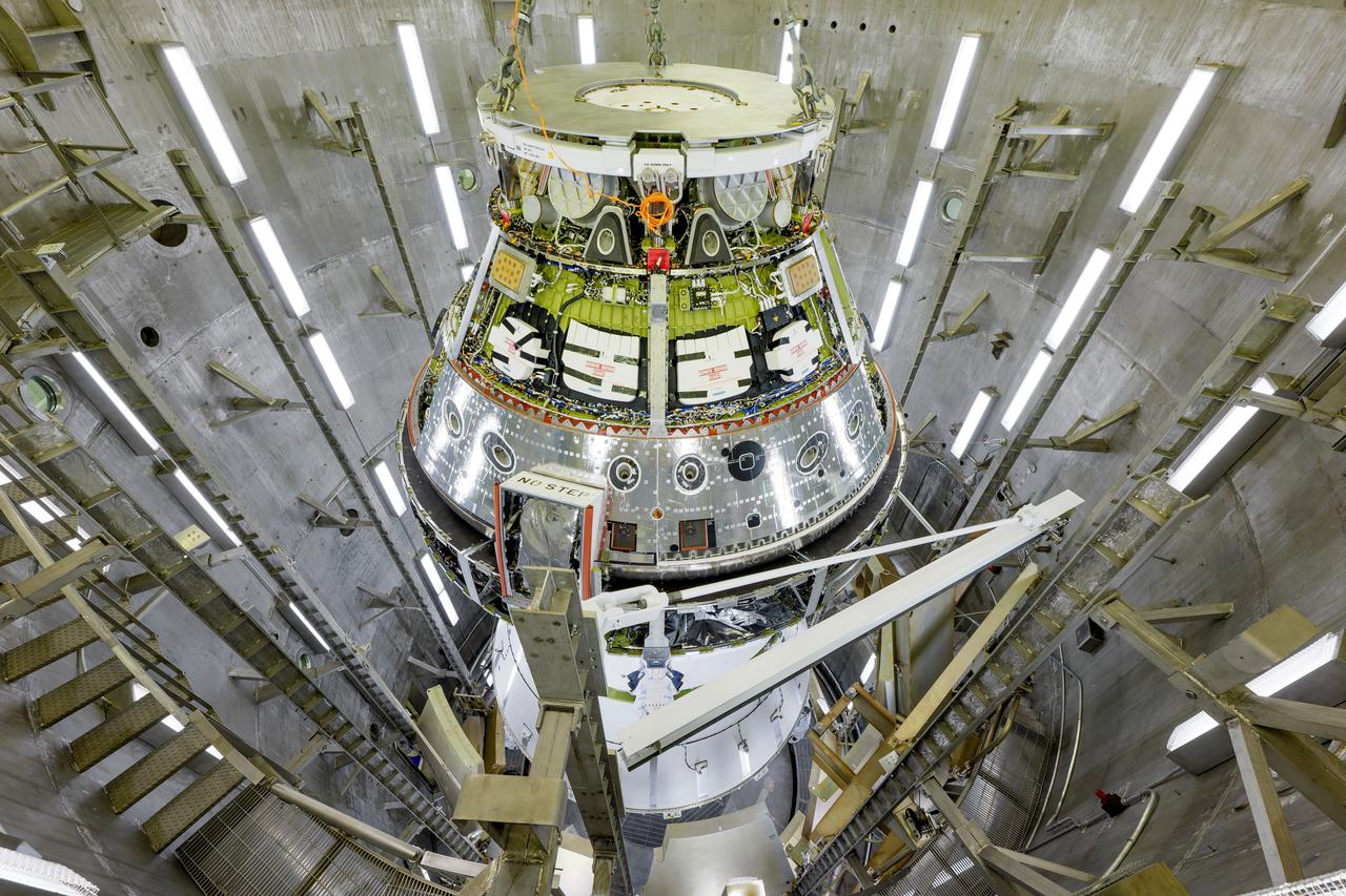 The Artemis II Orion spacecraft is lifted from the Final Assembly and System Testing (FAST) Cell and placed in the west altitude chamber inside the Operations and Checkout Building at NASA’S Kennedy Space Center in Florida on June 28, 2024. Inside the altitude chamber, the spacecraft underwent a series of tests simulating deep space vacuum conditions. Photo Credit: NASA / Rad Sinyak 