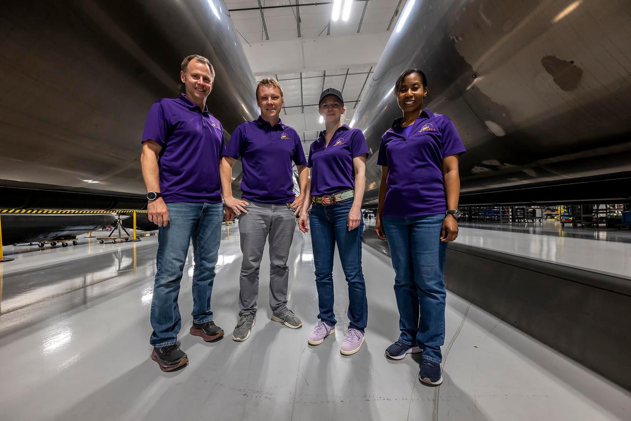 jsc2024e050139 (May 13, 2024) --- NASA’s SpaceX Crew-9 members pose for a photo in between Falcon 9 first-stage boosters that are being refurbished at SpaceX’s HangarX facility at NASA's Kennedy Space Center in Florida for future launches. From left are, Pilot Nick Hague from NASA; Mission Spedialist Alexsandr Gorbunov from Roscosmos; Commander Zena Cardman from NASA; and Mission Specialist Stephanie Wilson from NASA. Credit: SpaceX