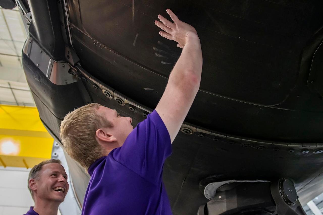 jsc2024e050143 (May 13, 2024) --- From left, SpaceX Crew-9 Pilot Nick Hague from NASA and Mission Specialist Aleksandr Gorbunov check out a Falcon 9 first-stage booster at SpaceX’s HangarX facility at NASA's Kennedy Space Center in Florida. Credit: SpaceX