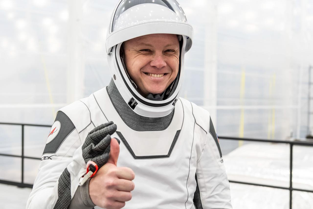 jsc2024e052325 (July 22, 2024) --- NASA’s SpaceX Crew-9 Mission Specialist Aleksandr Gorbunov gives a thumbs-up while wearing his flight suit during a successful crew equipment interface test (CEIT), of which the crew practiced donning their flight suits, performed a suited ingress into the spacecraft, conducted suit leak checks, and completed communication checkouts. Credit: SpaceX